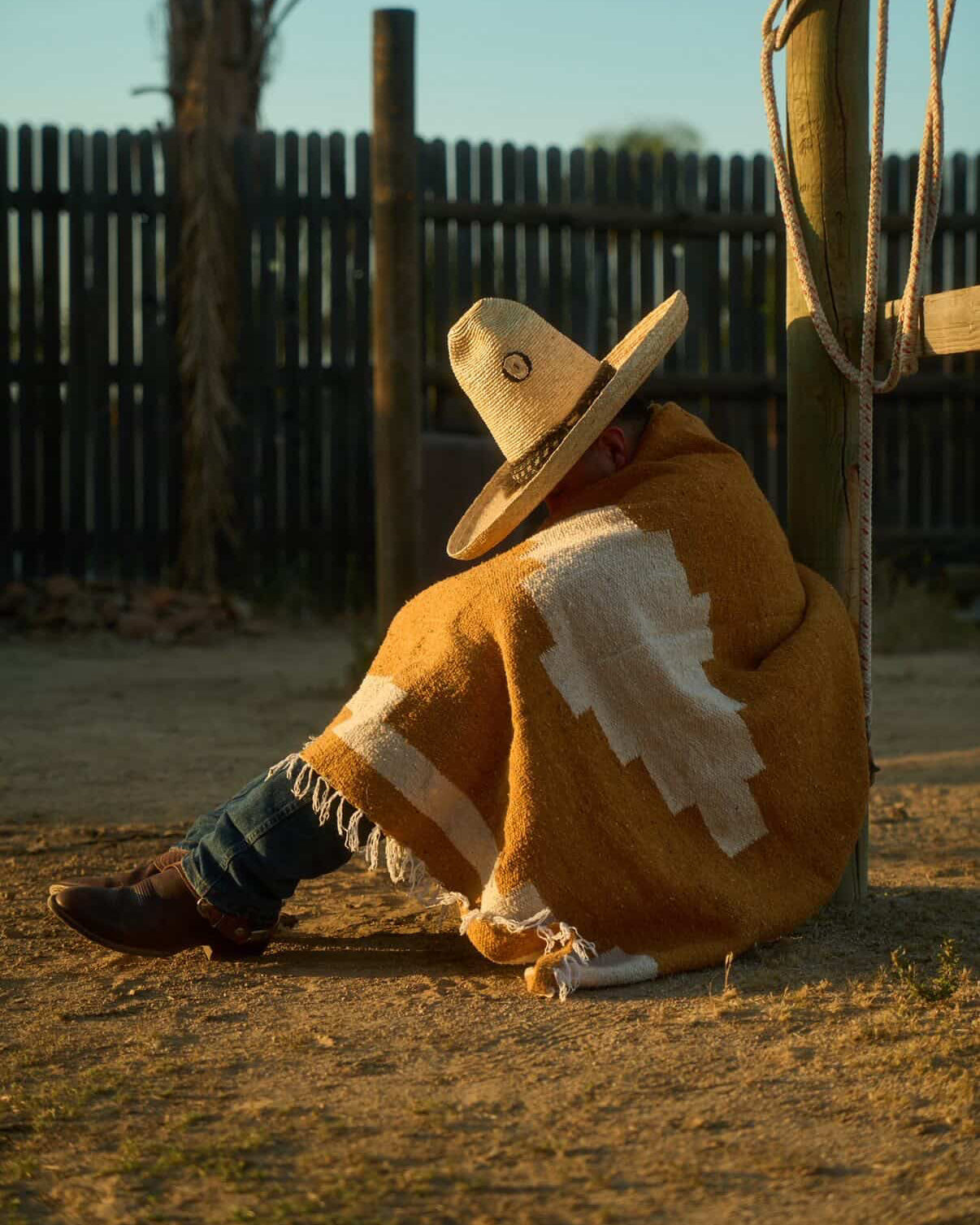 Man in sombrero wearing old handwoven mexican blankt sitting on the ground