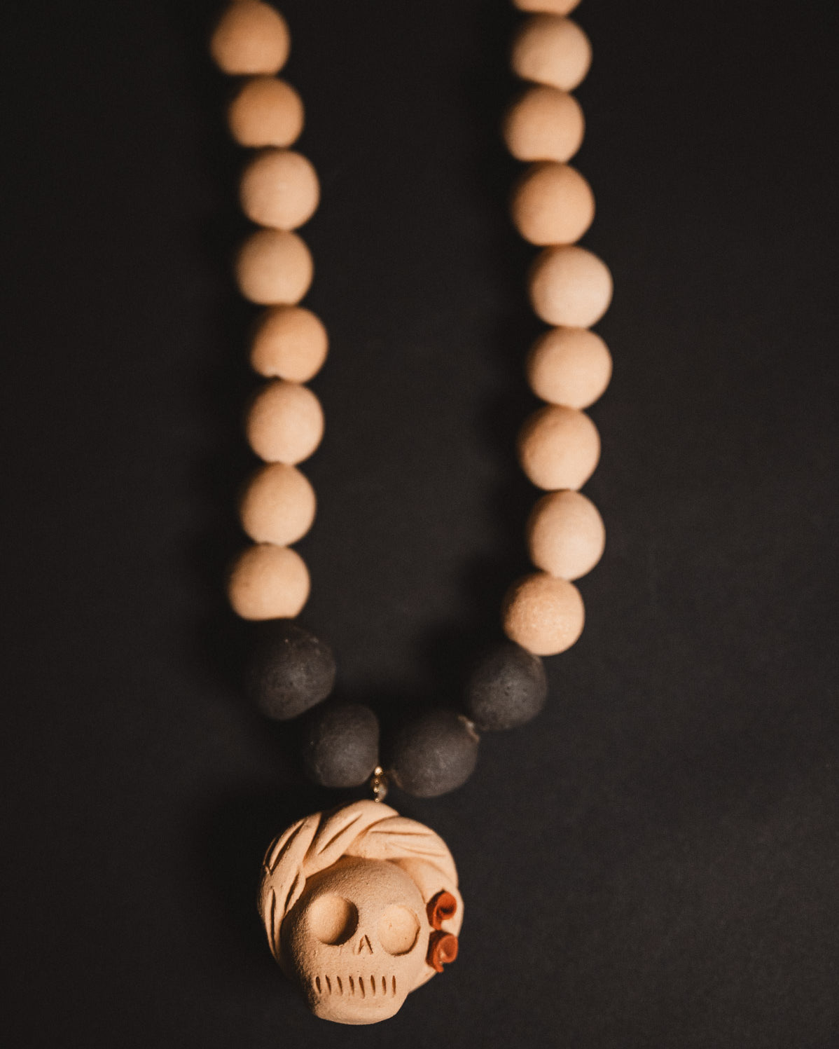 Necklace with wooden beads and a skull pendant on a dark background