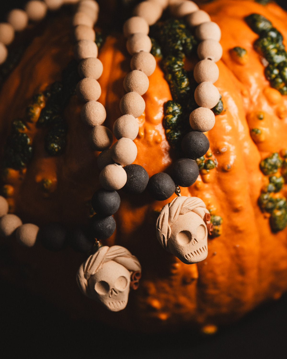 Decorative beaded necklace with skull pendants on a pumpkin background