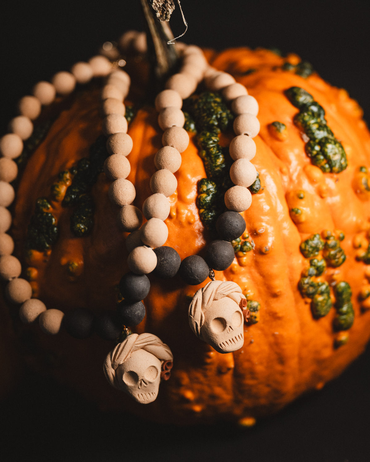 Decorative pumpkin with beaded necklace and skull pendant on a dark background