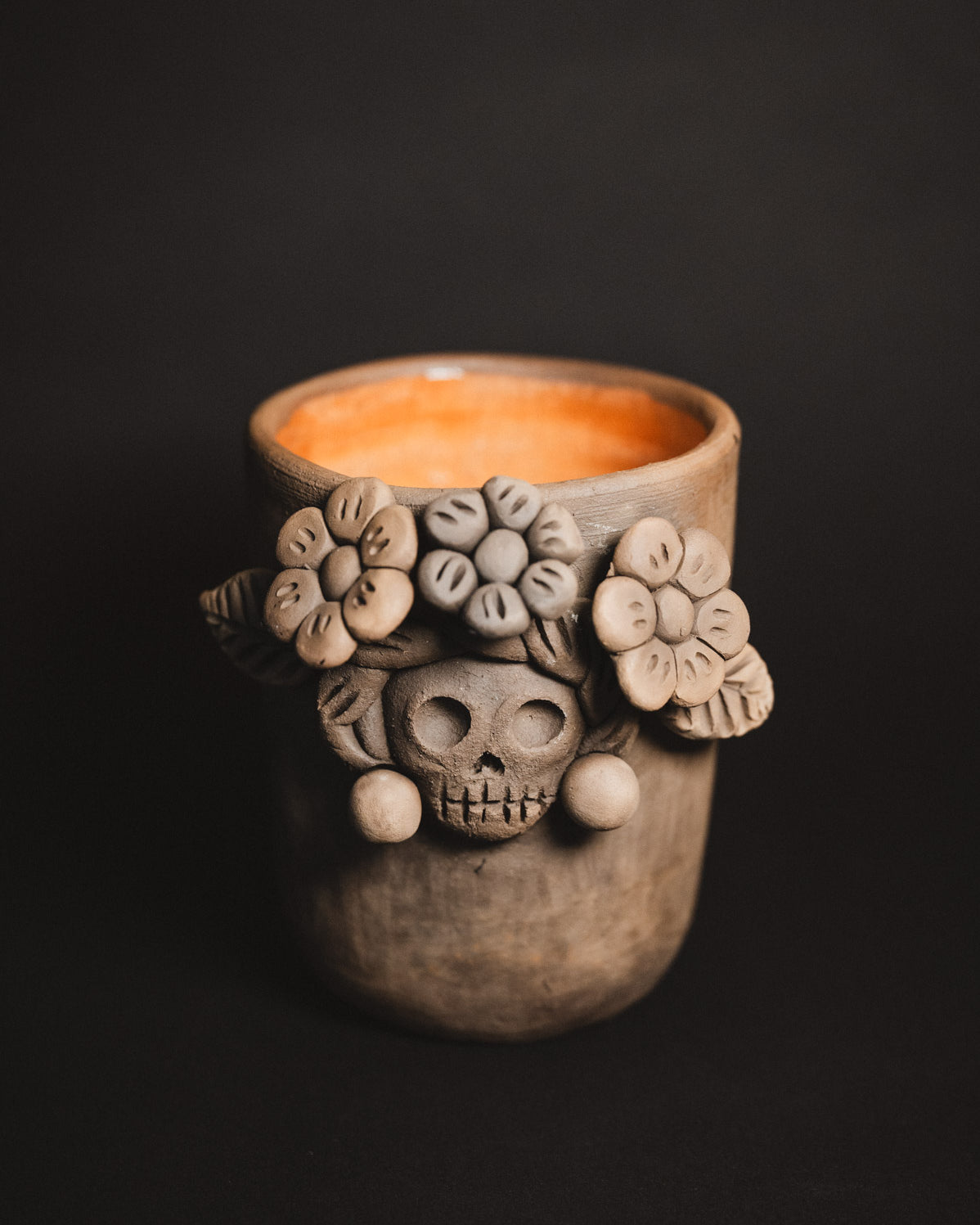 Ceramic cup with skull and floral design on a black background