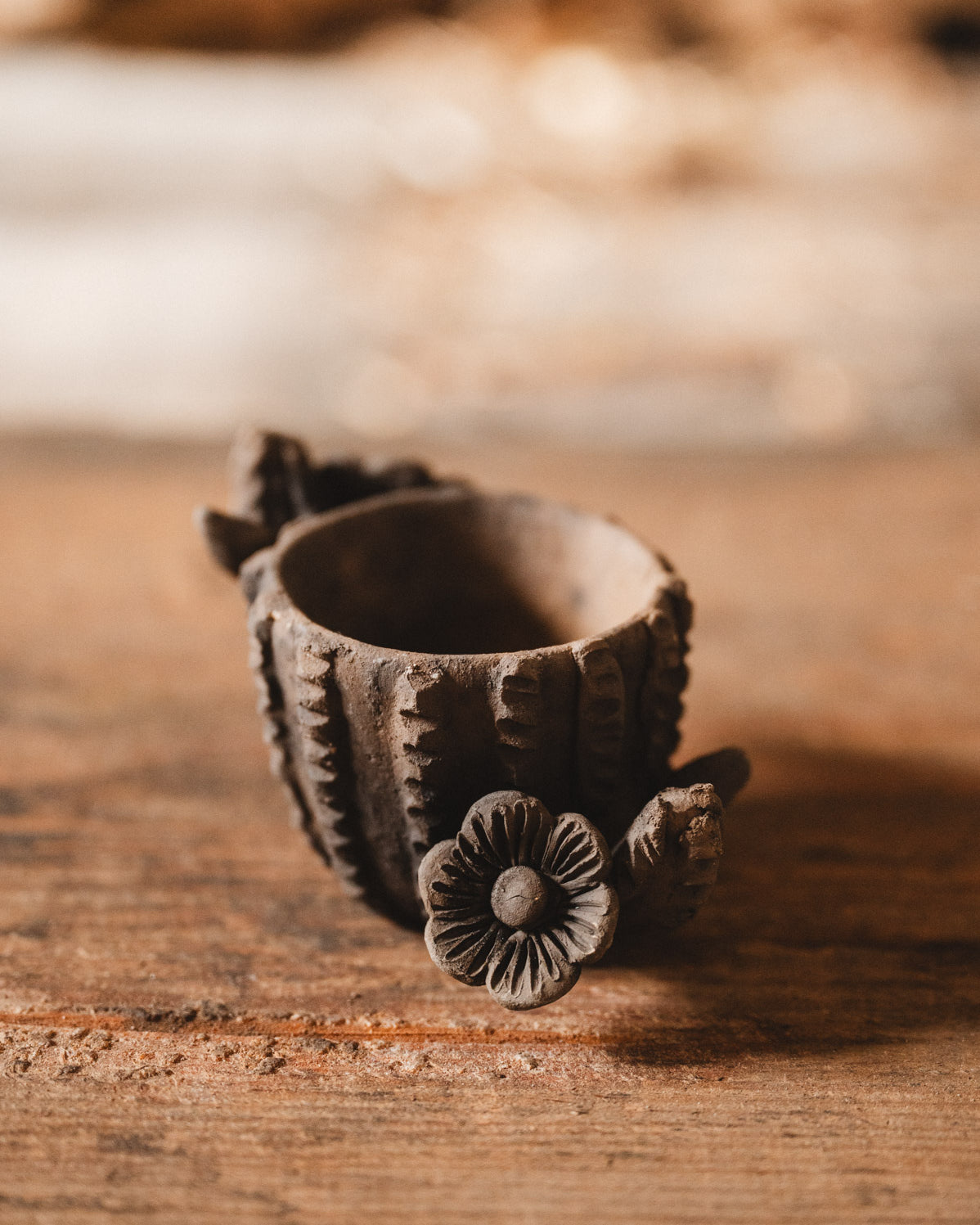 Decorative clay cactus planter with floral design on a wooden surface