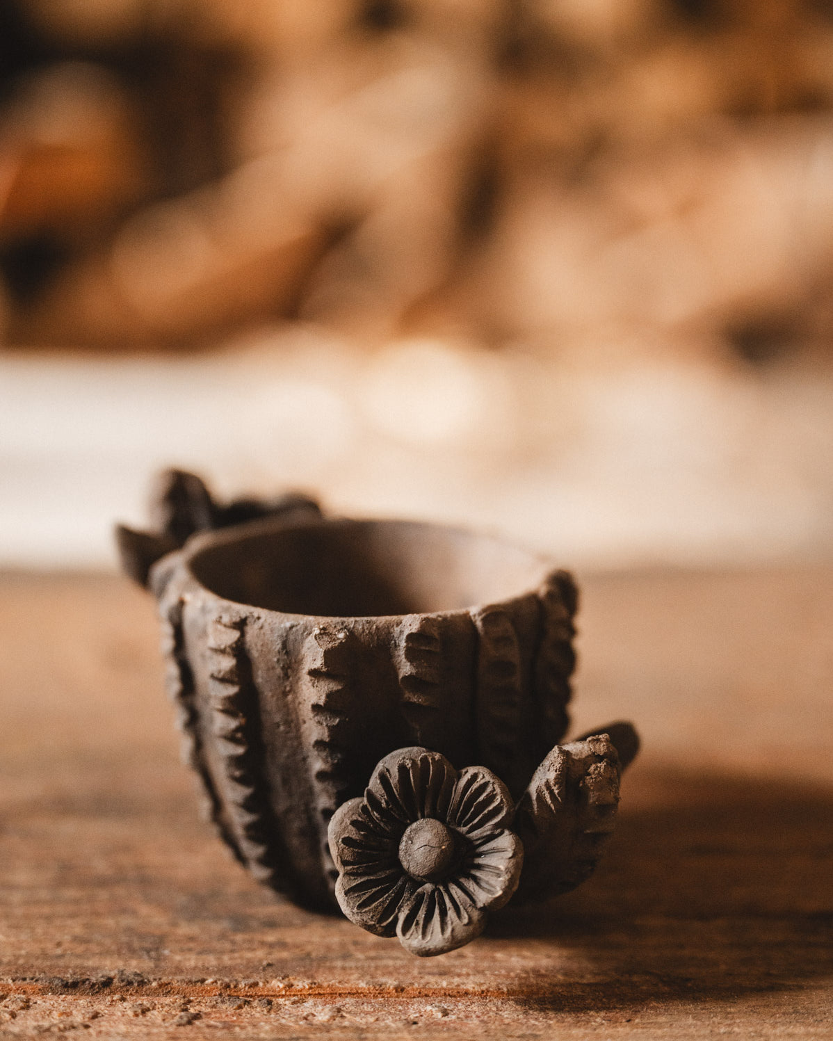 Decorative clay cactus planter with floral design on a wooden surface