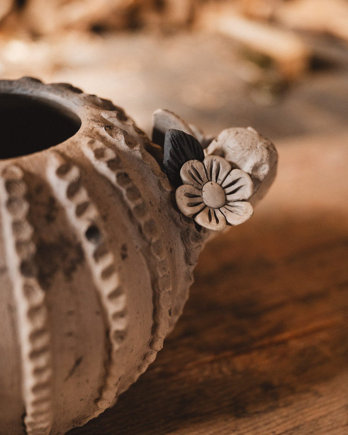 Ceramic cactus planter with floral design on a wooden surface with blurred woodpile background