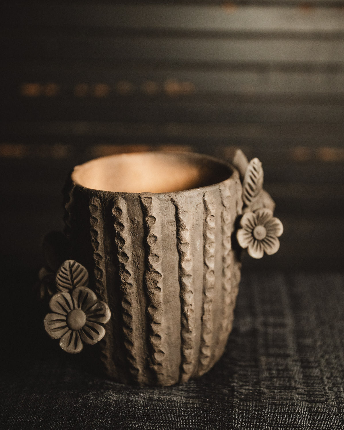 Ceramic planter with floral designs on a dark textured background
