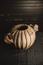 Ceramic planter with textured surface and floral decorations on a dark background