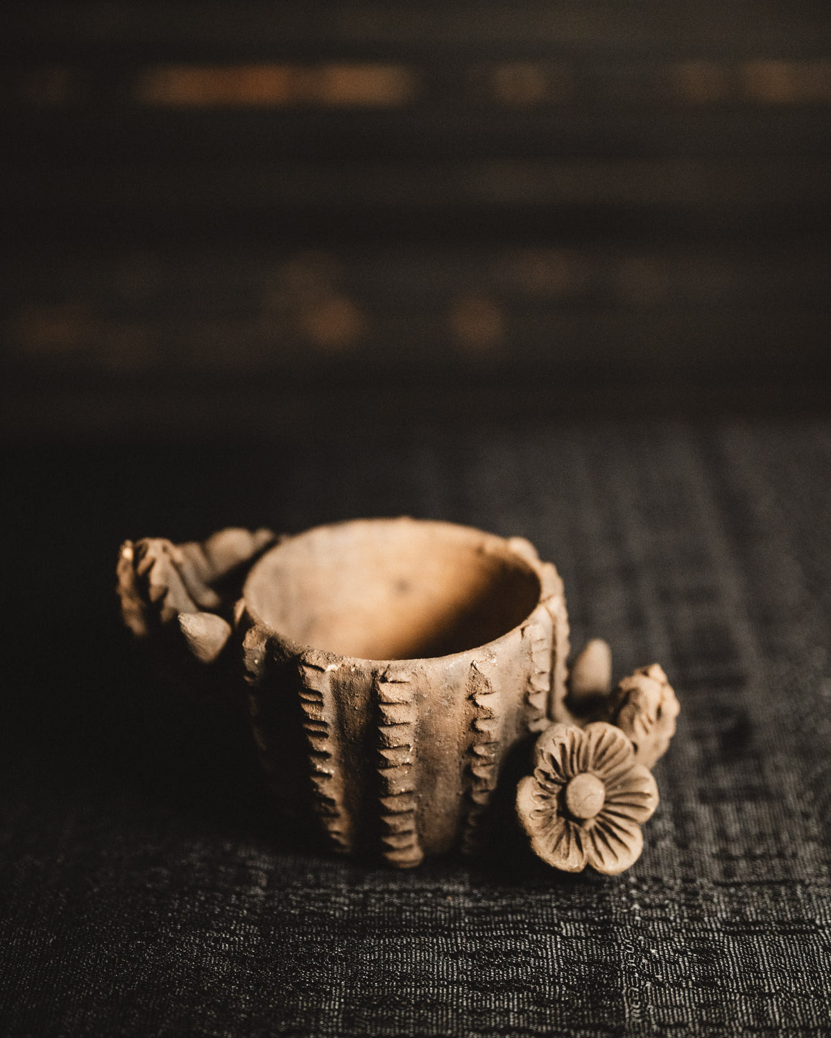 Decorative ceramic planter with floral design on a dark textured surface