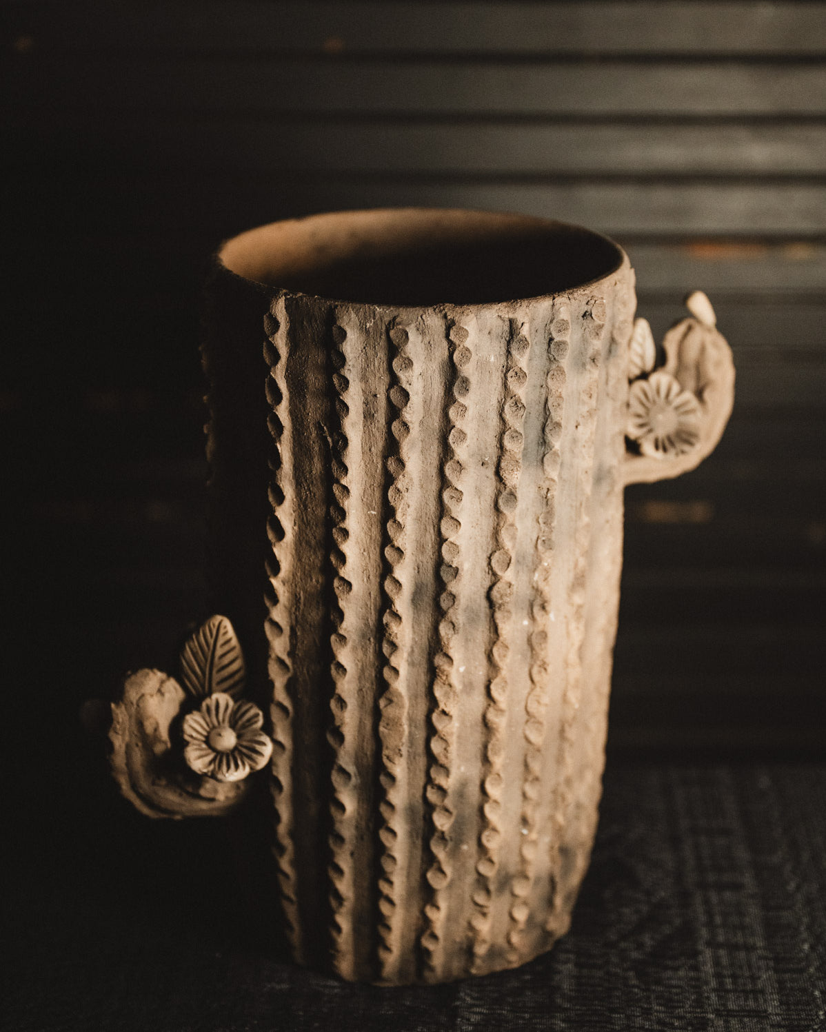 Decorative ceramic planter with floral designs on a dark background