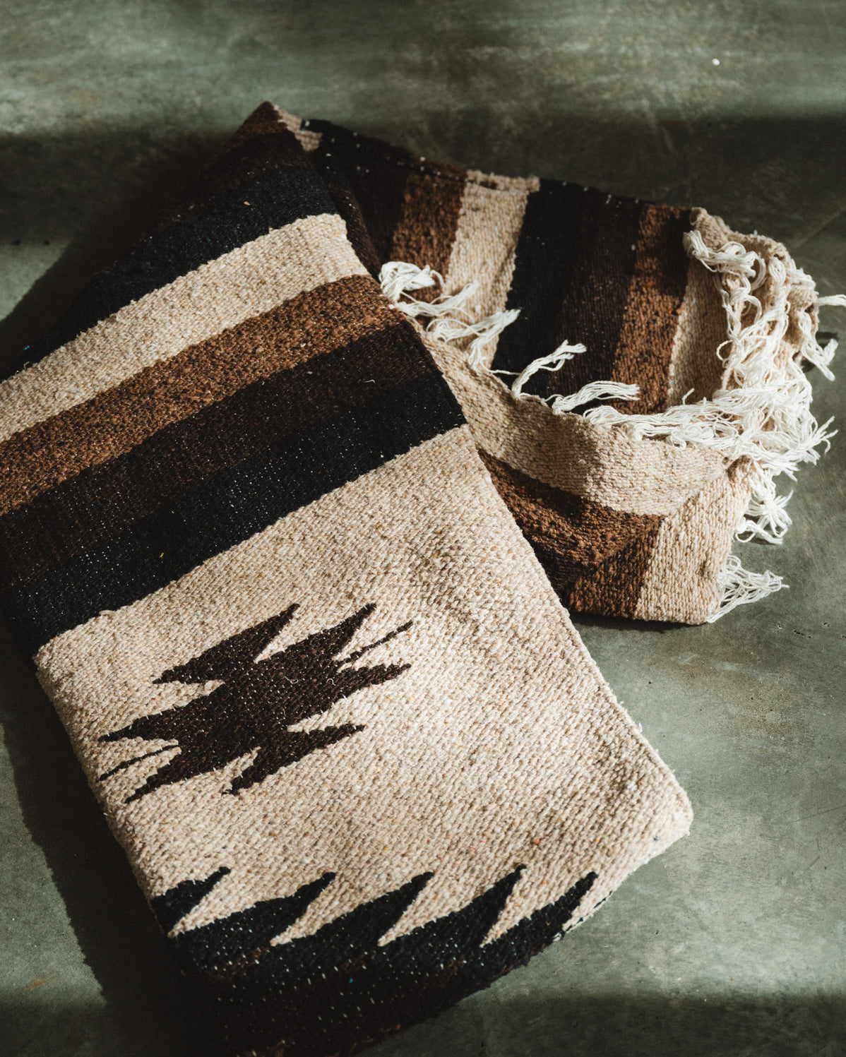 Handwoven brown and beige diamond mexican blanket folded on ground