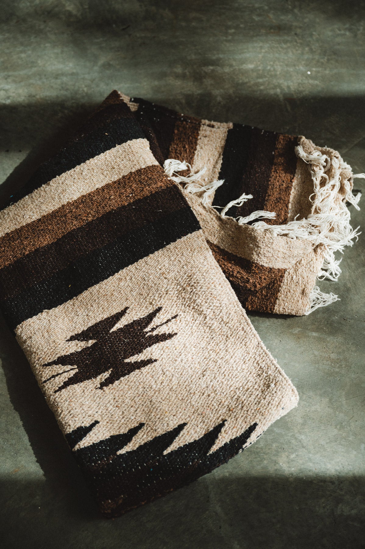 Handwoven brown and beige diamond mexican blanket folded on ground