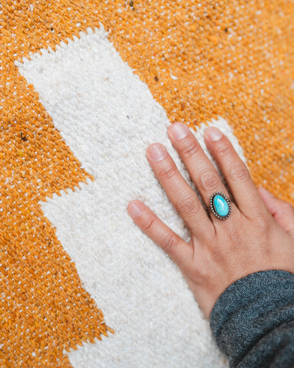 Orange handwoven blanket and hand with turquoise ring