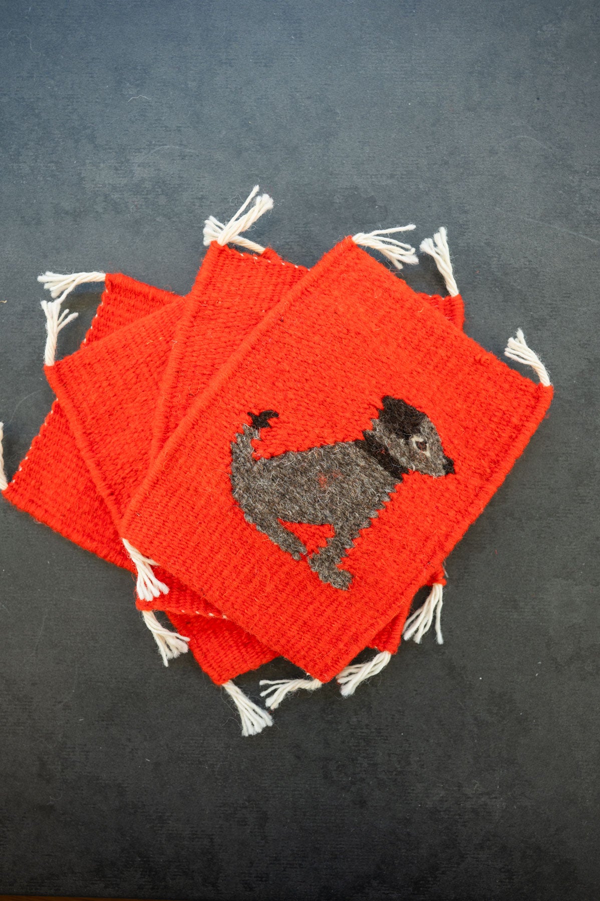 Handwoven wool coaster from Teotitlan Del Valle of a Dog on red background