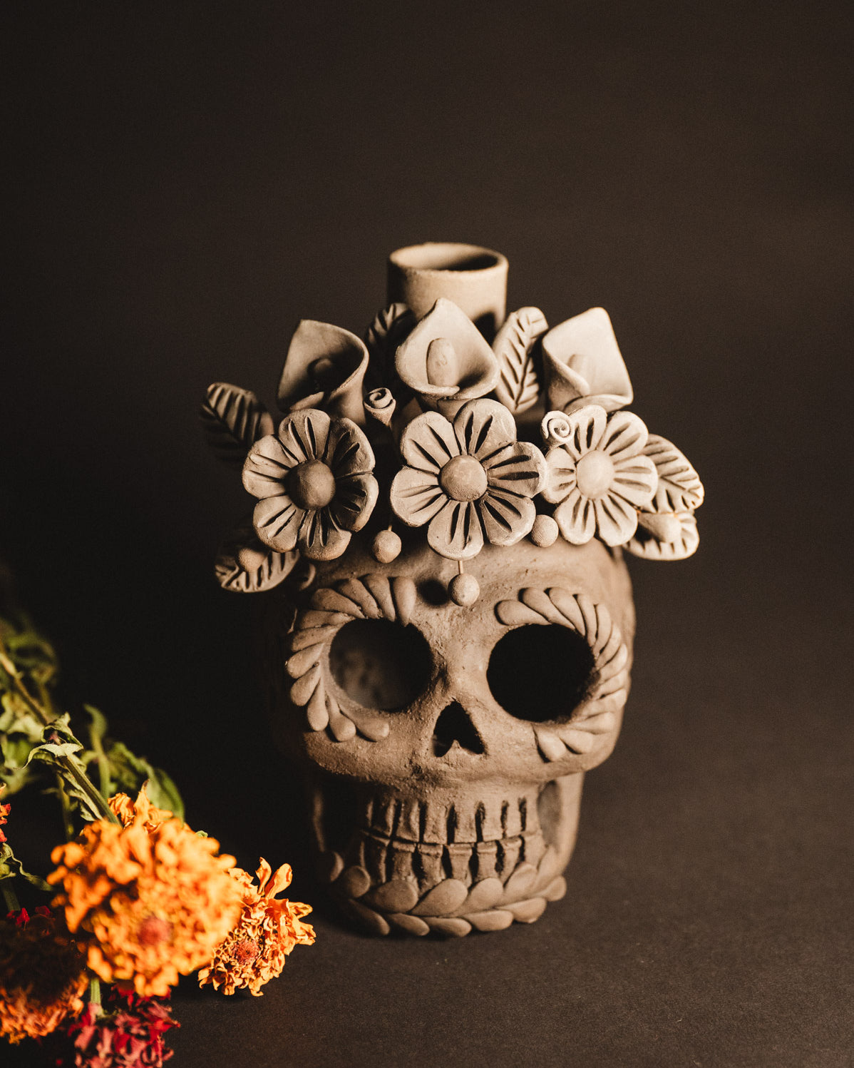 Ceramic skull vase with floral decorations on a dark background