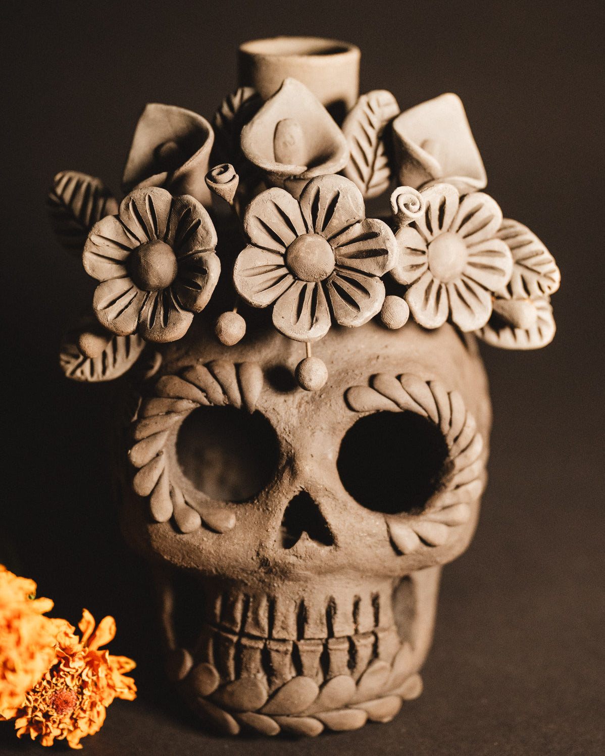 Ceramic skull vase with floral designs on a dark background