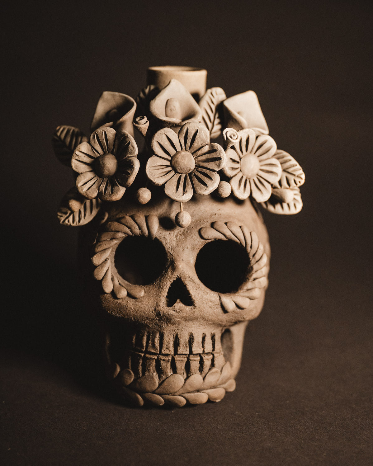 Clay skull with floral design on a dark background