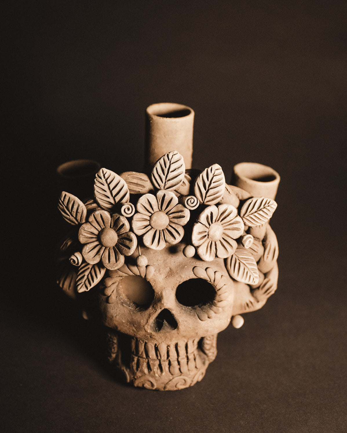 Ceramic skull vase with floral designs on a dark background