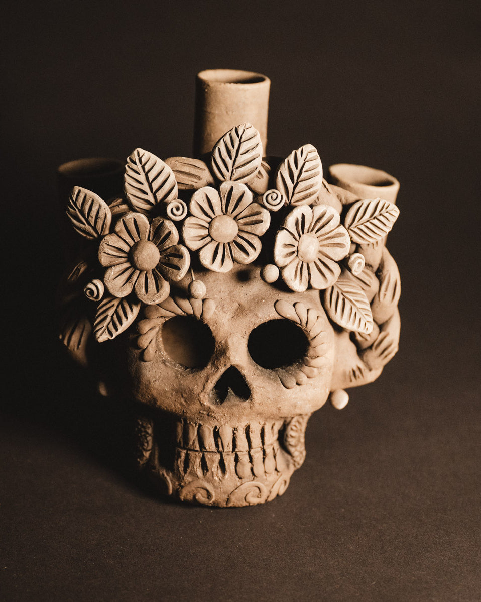 Ceramic skull vase with floral design on a dark background