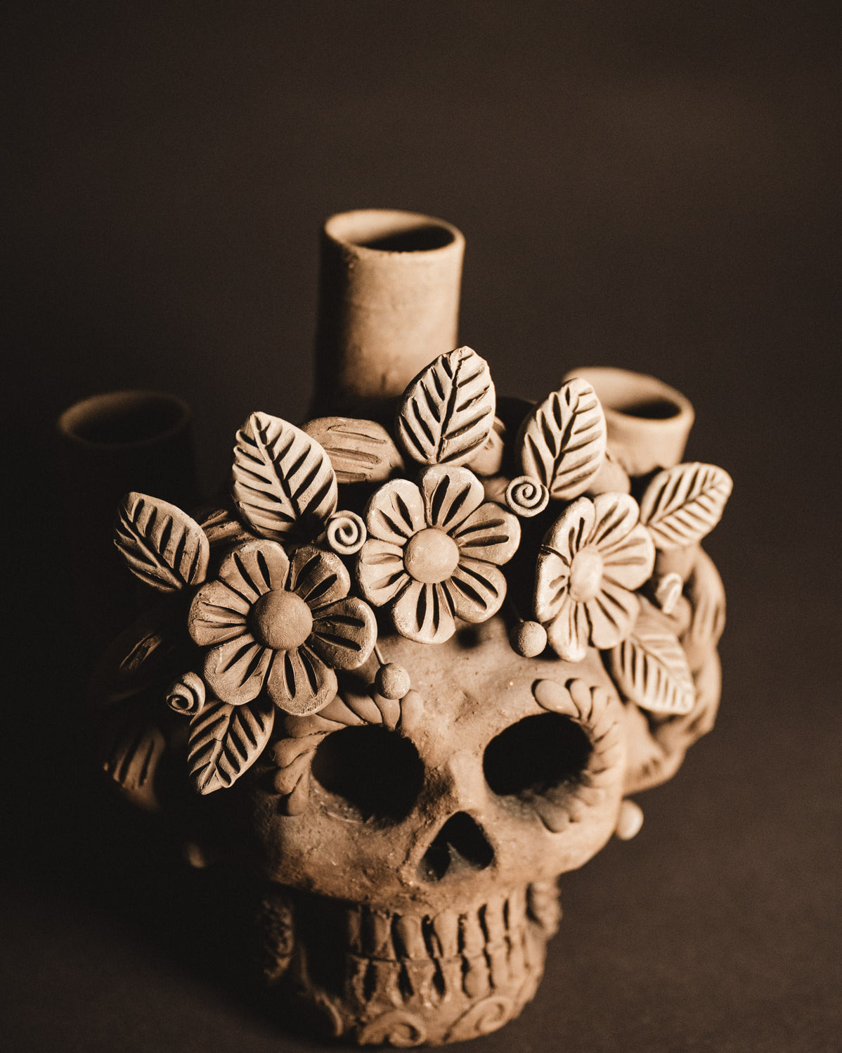 Ceramic skull vase with floral designs on a dark background