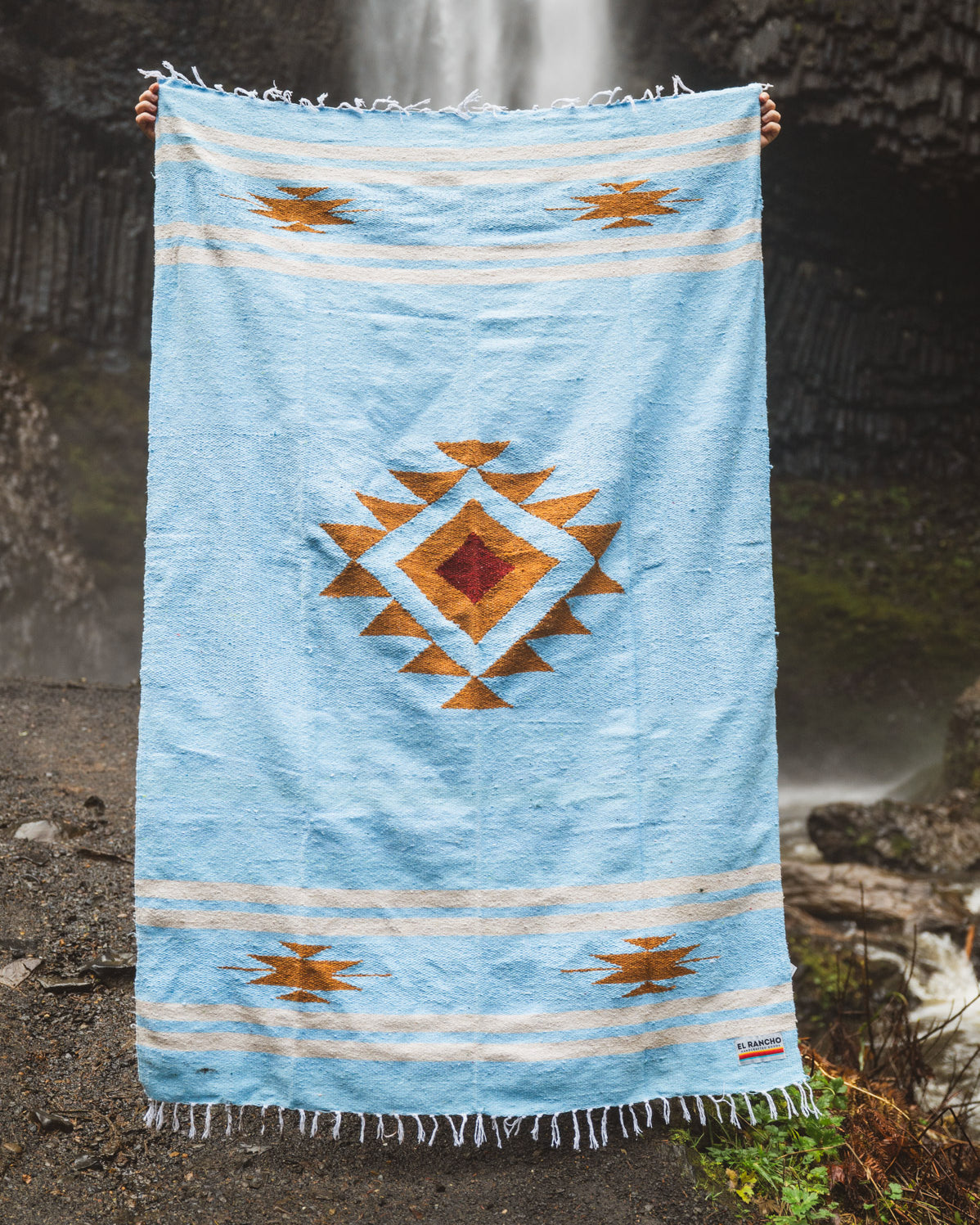 Blue patterned towel held up against a waterfall background