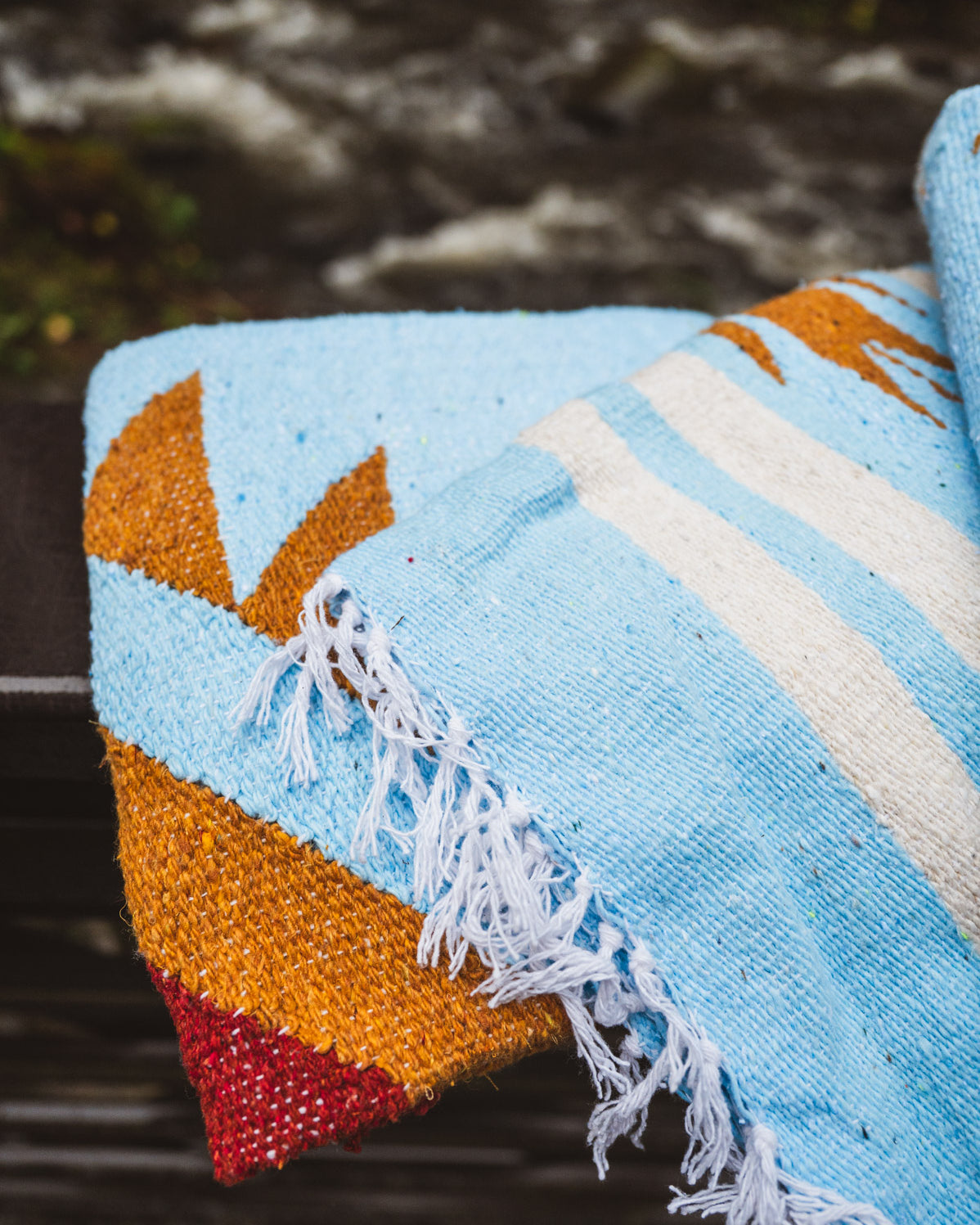 Colorful woven blanket with geometric pattern on a natural background