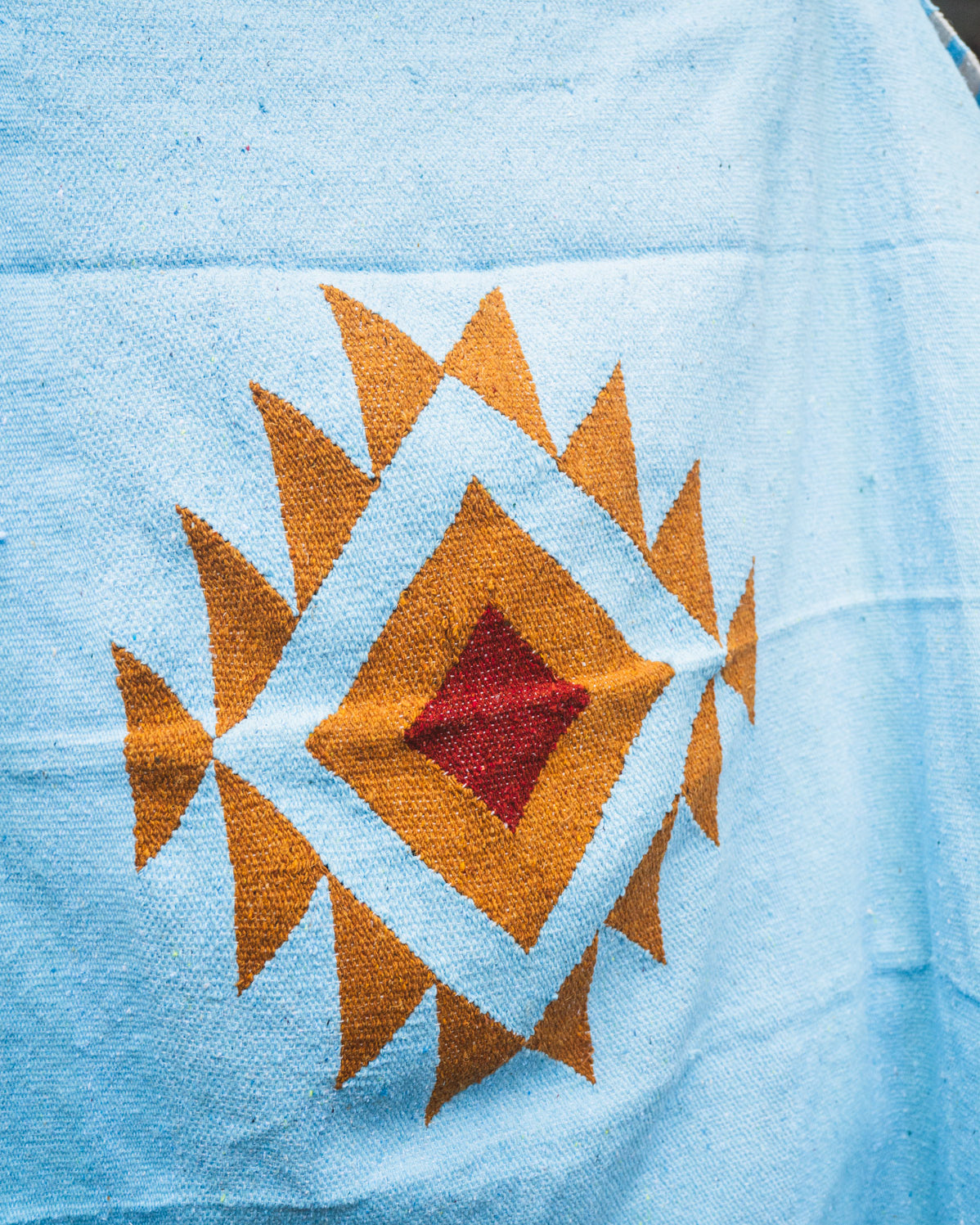 Blue fabric with a geometric pattern featuring orange and red colors.