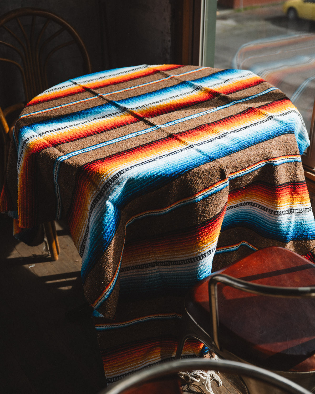 Colorful striped blanket draped over a table and chairs in an outdoor setting