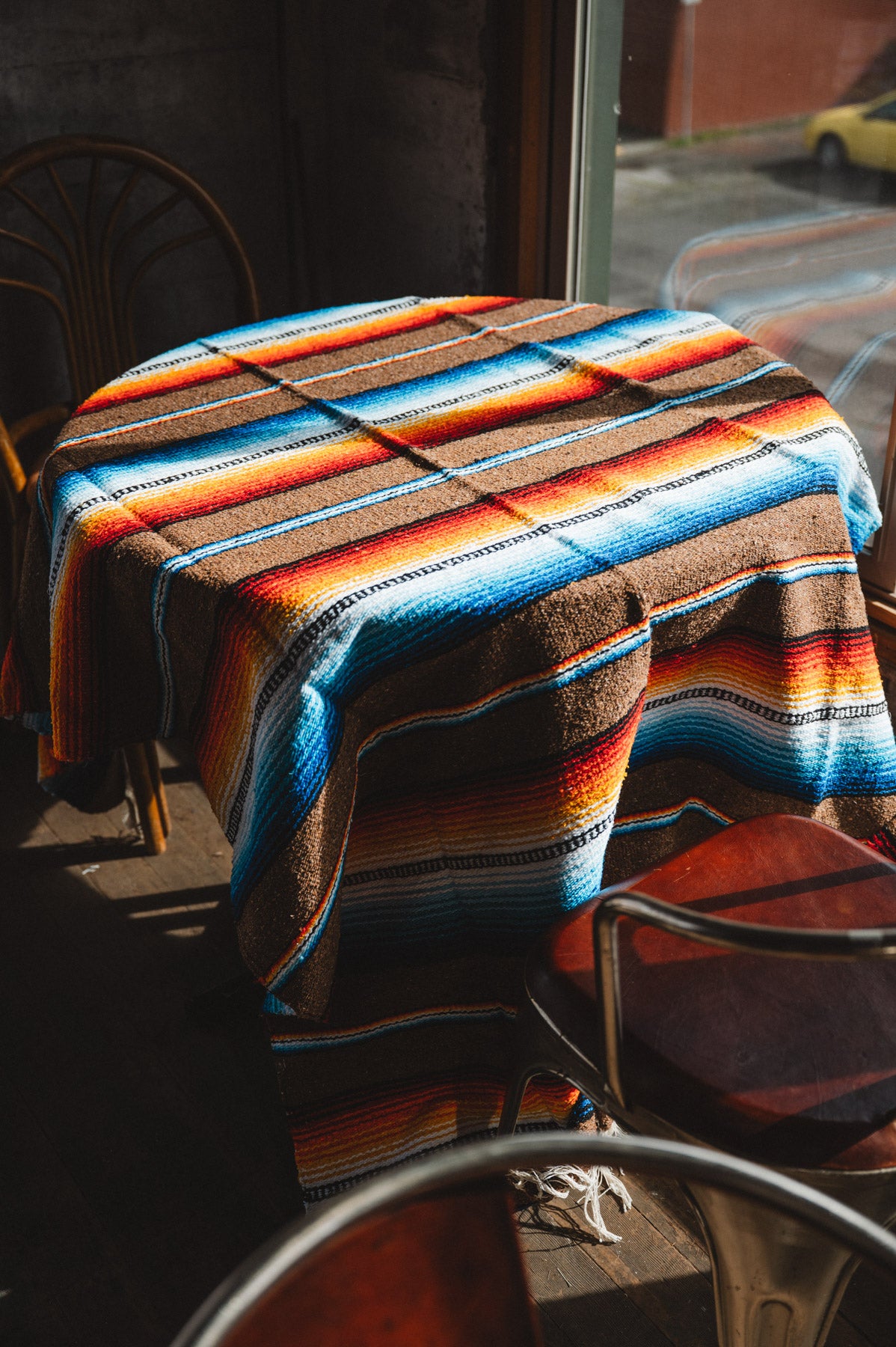 Colorful striped blanket draped over a table and chairs in an outdoor setting