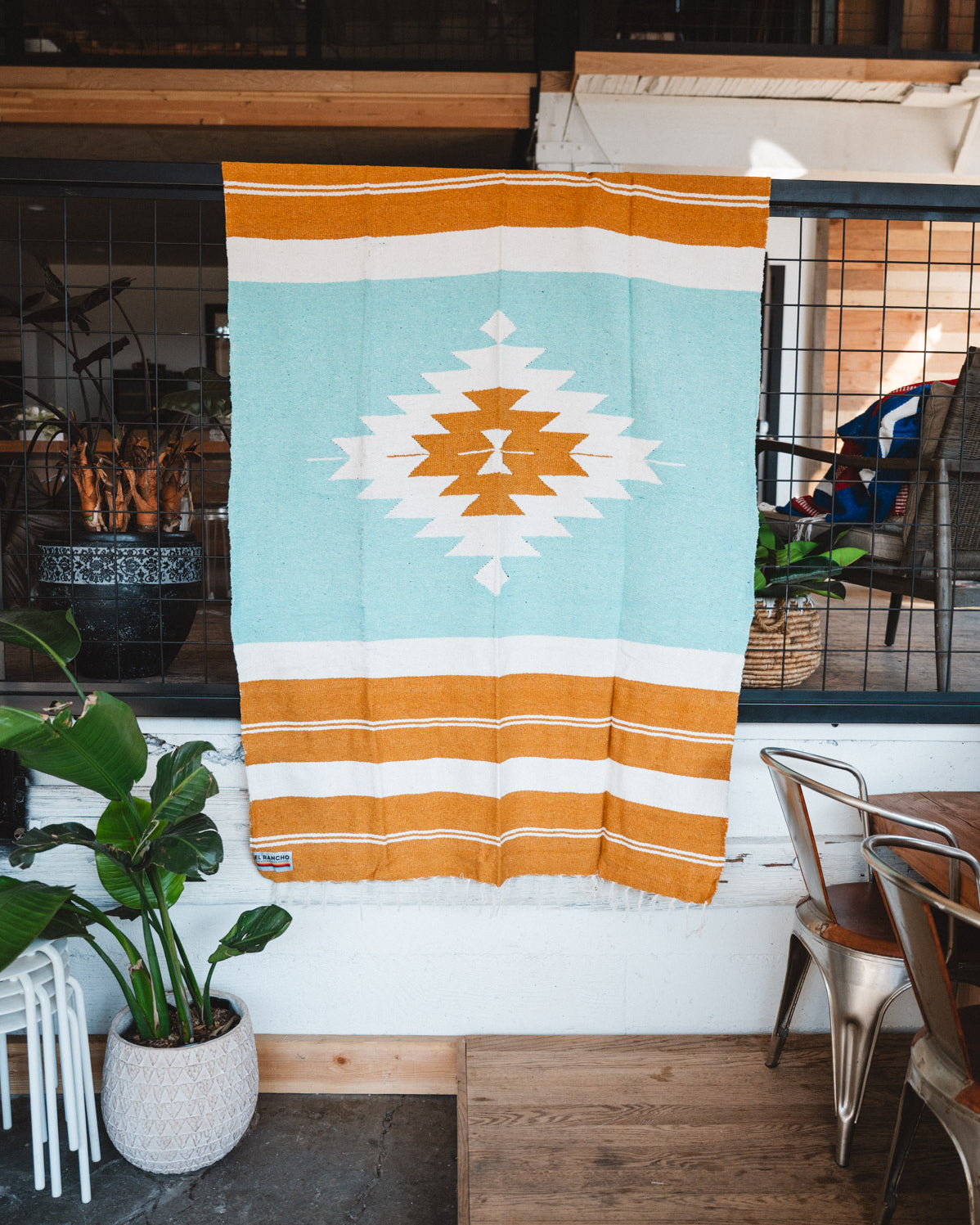 andwoven Mexican Blanket Turquoise and gold color Diamond pattern in modern industrial setting