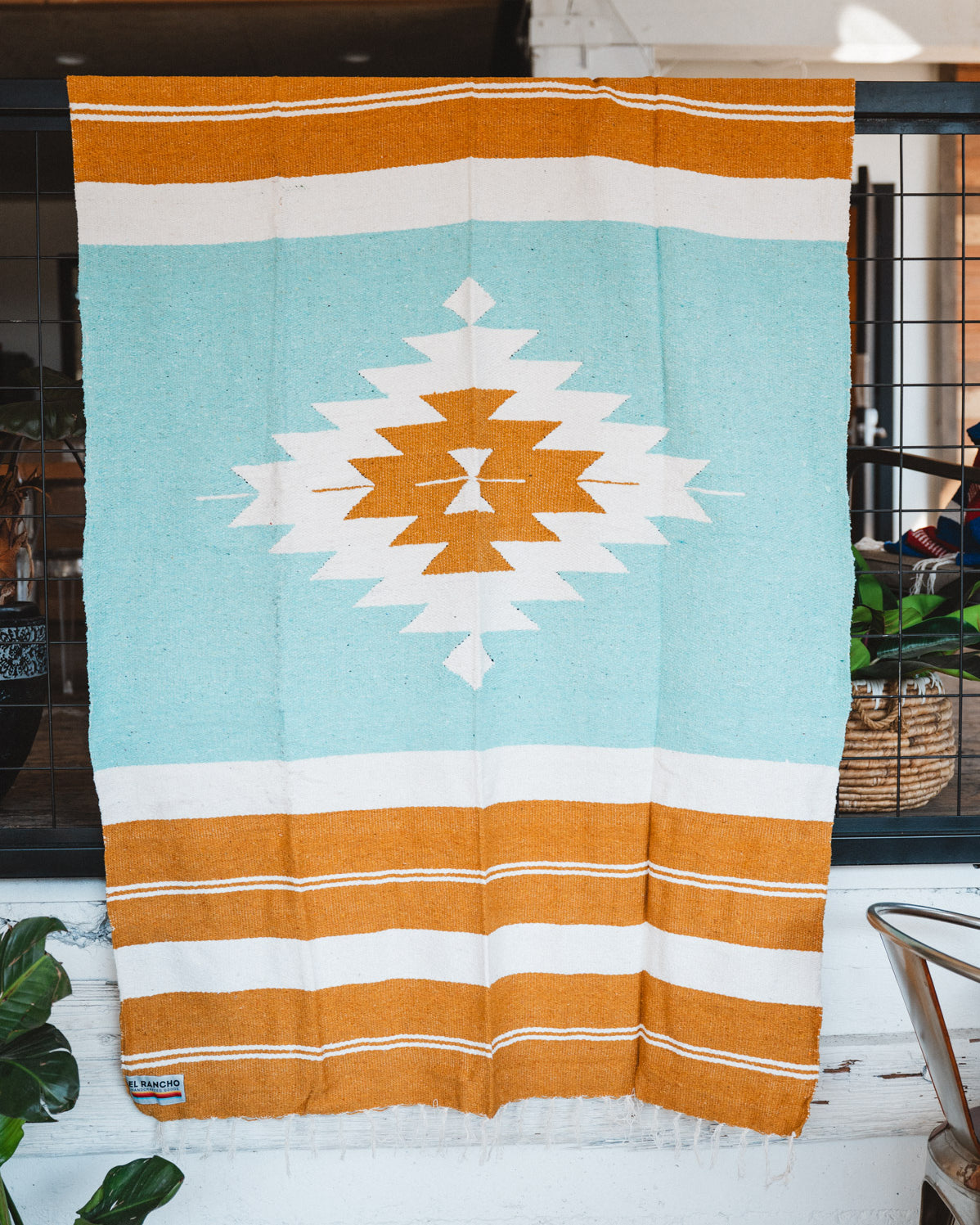 andwoven Mexican Blanket Turquoise and gold color Diamond pattern in modern industrial setting