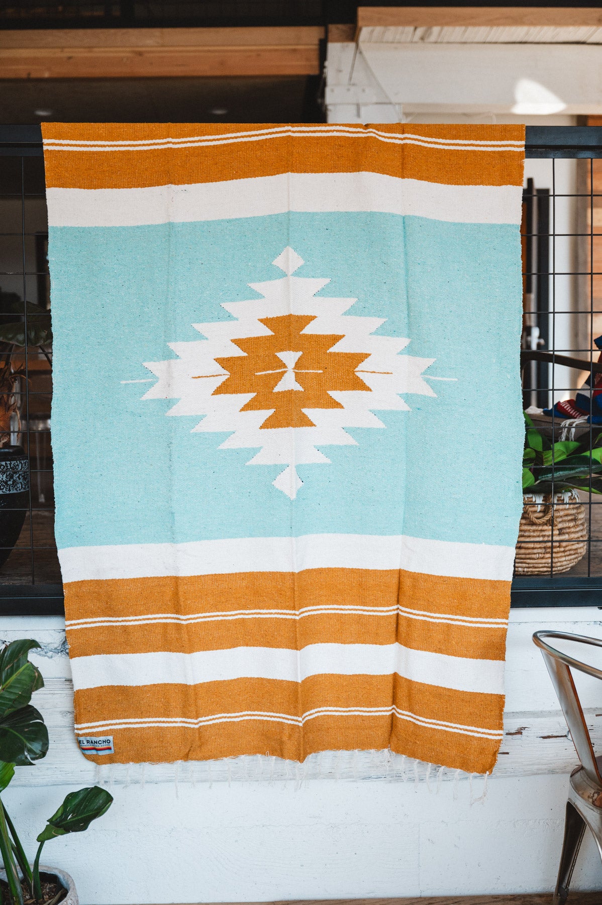 andwoven Mexican Blanket Turquoise and gold color Diamond pattern in modern industrial setting