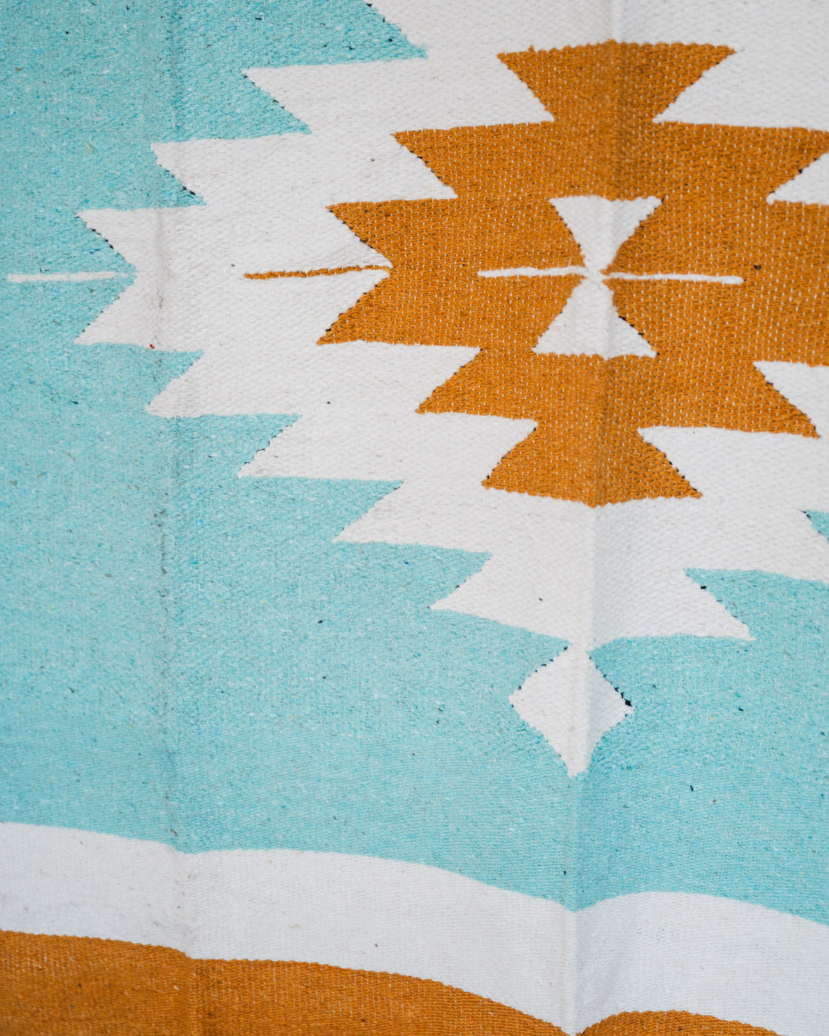 andwoven Mexican Blanket Turquoise and gold color Diamond pattern in modern industrial setting