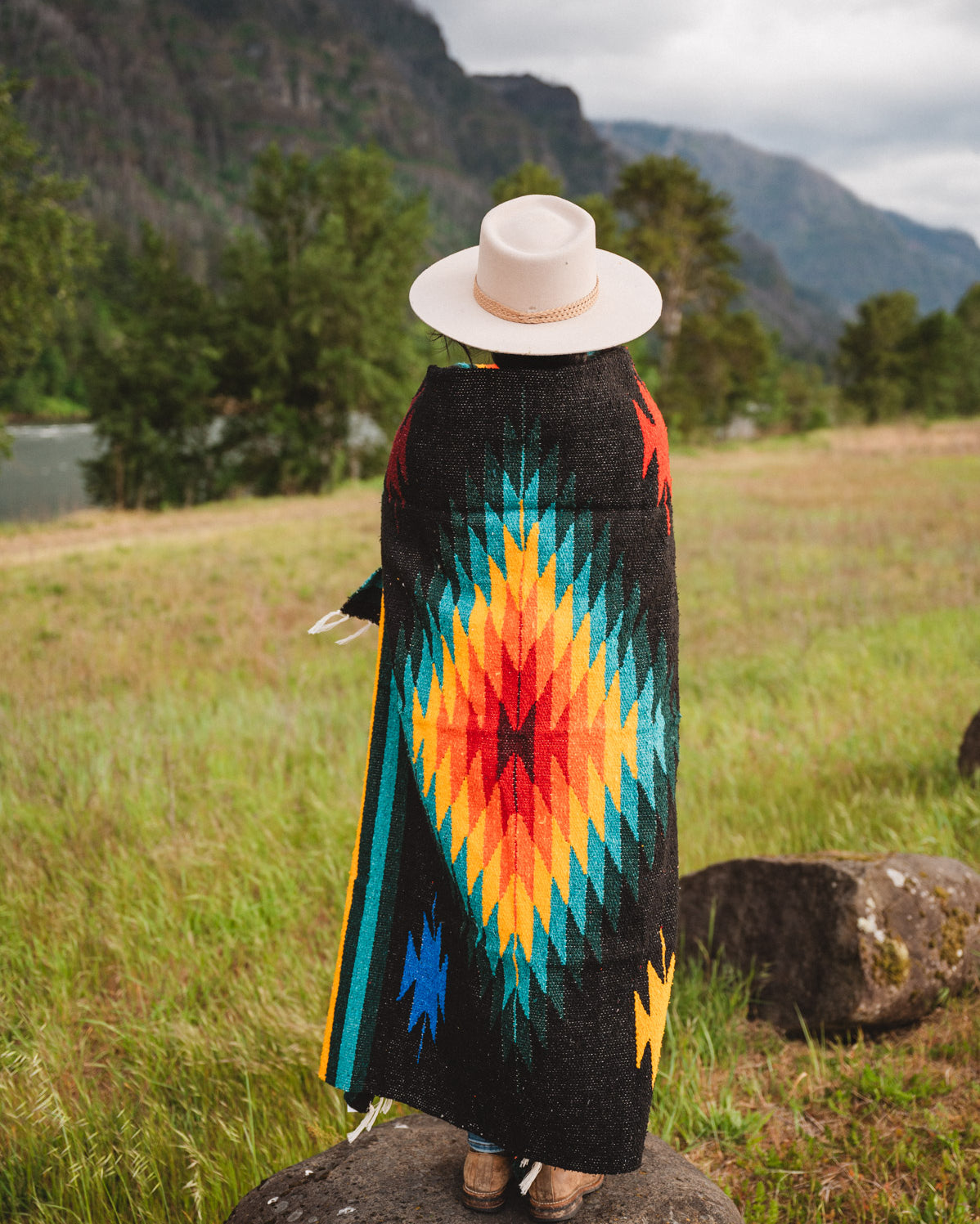 Mexican woman warpped in a multicolored handwoven mexican blanket with greca designs