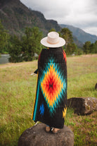 Mexican woman warpped in a multicolored handwoven mexican blanket with greca designs