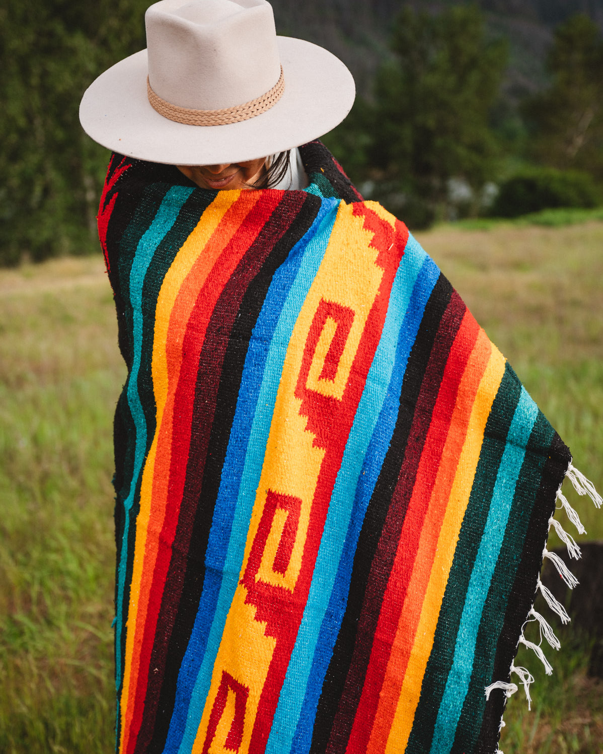 Mexican woman wrapped in a multicolored handwoven mexican blanket with greca designs