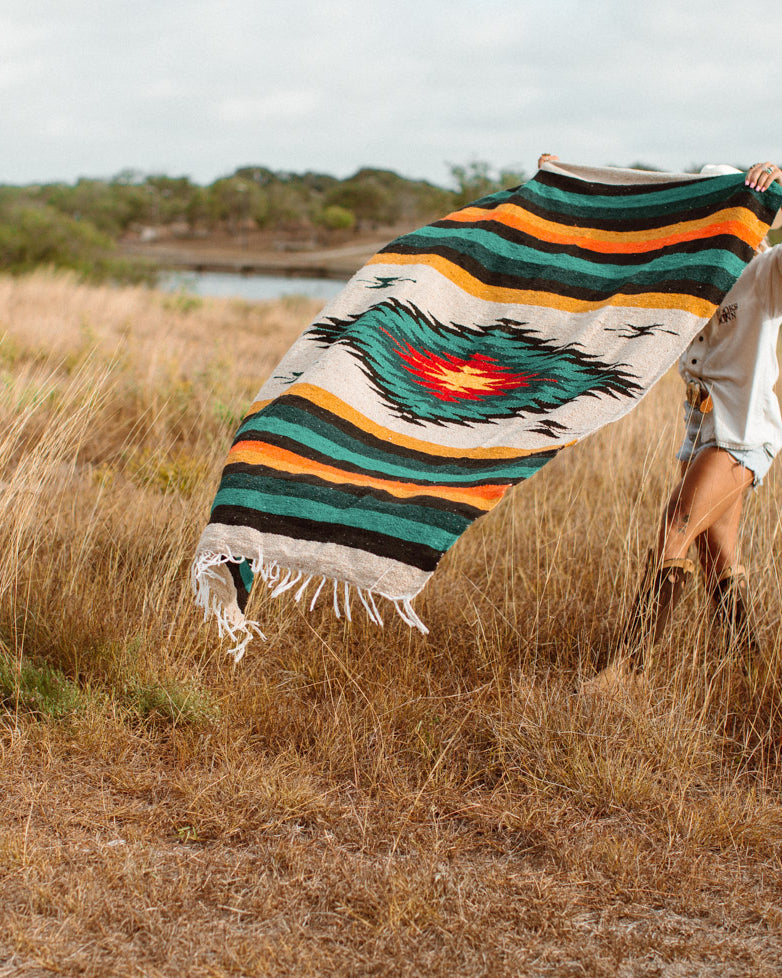 Girl spreading out diamond blanket in a field of tall dry grass