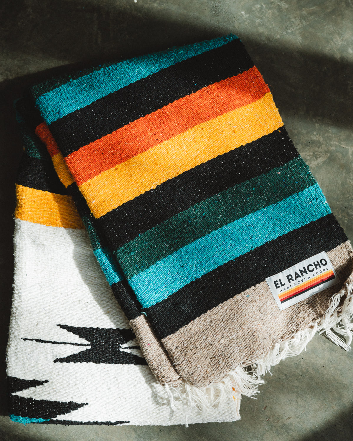 Green and white handwoven diamond mexican blanket folded on the ground