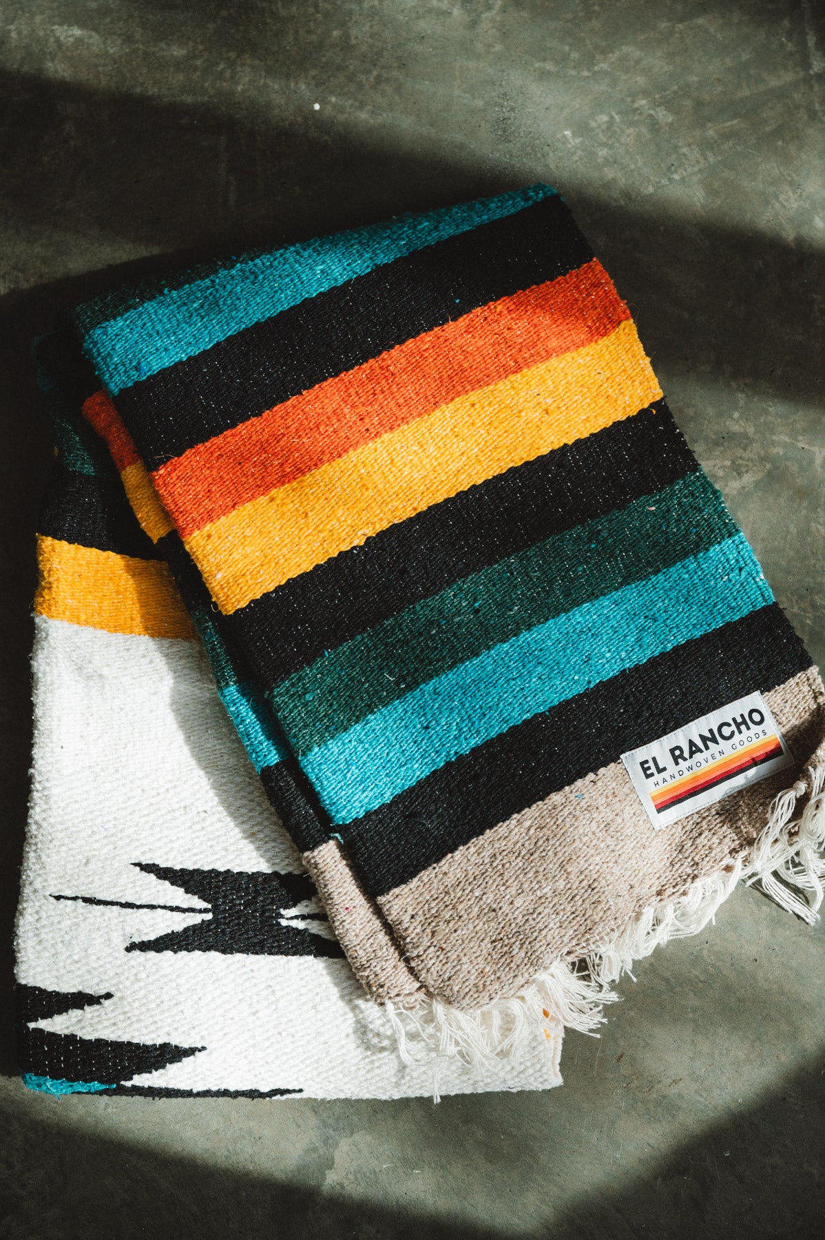 Green and white handwoven diamond mexican blanket folded on the ground