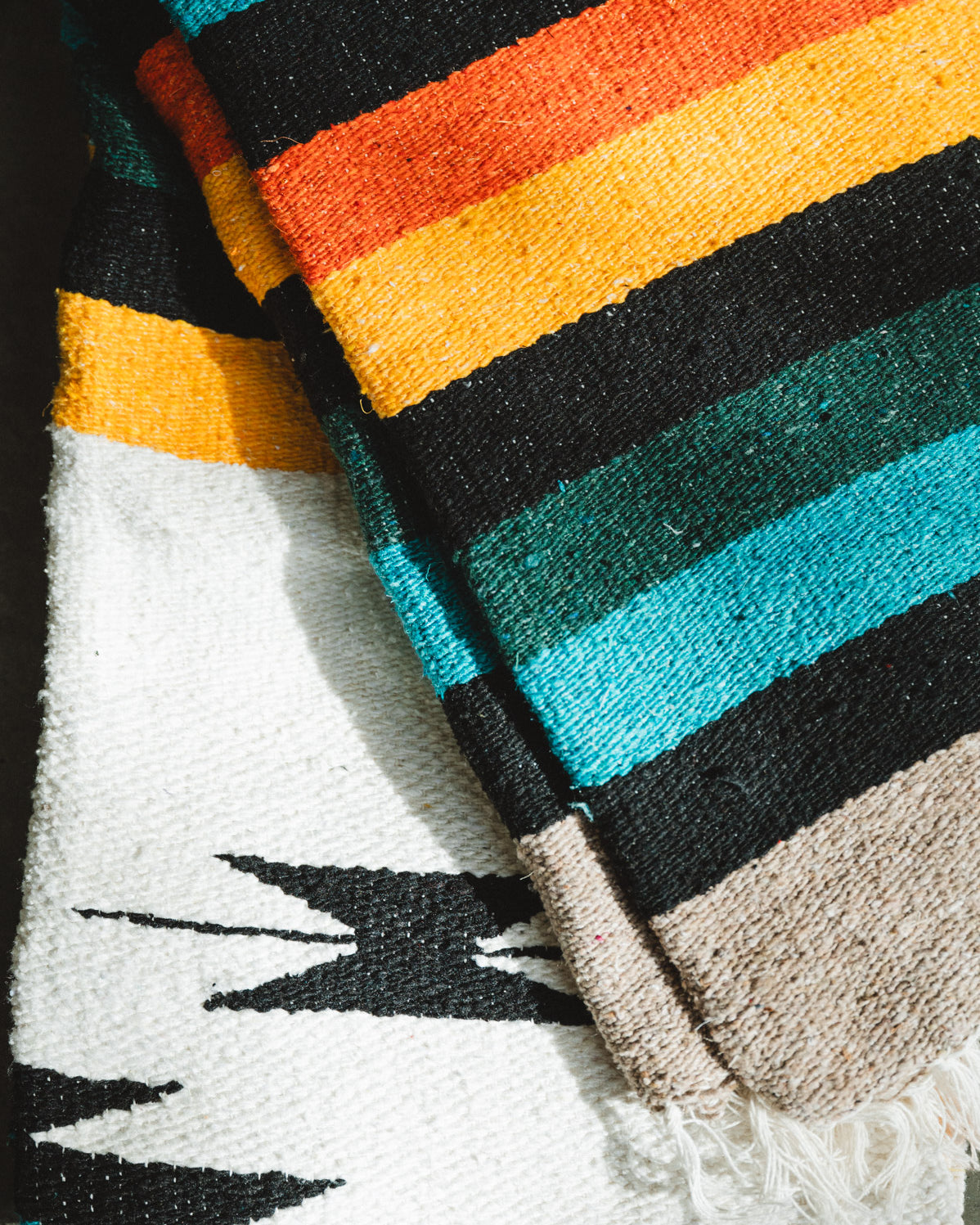 Green and white handwoven diamond mexican blanket folded on the ground