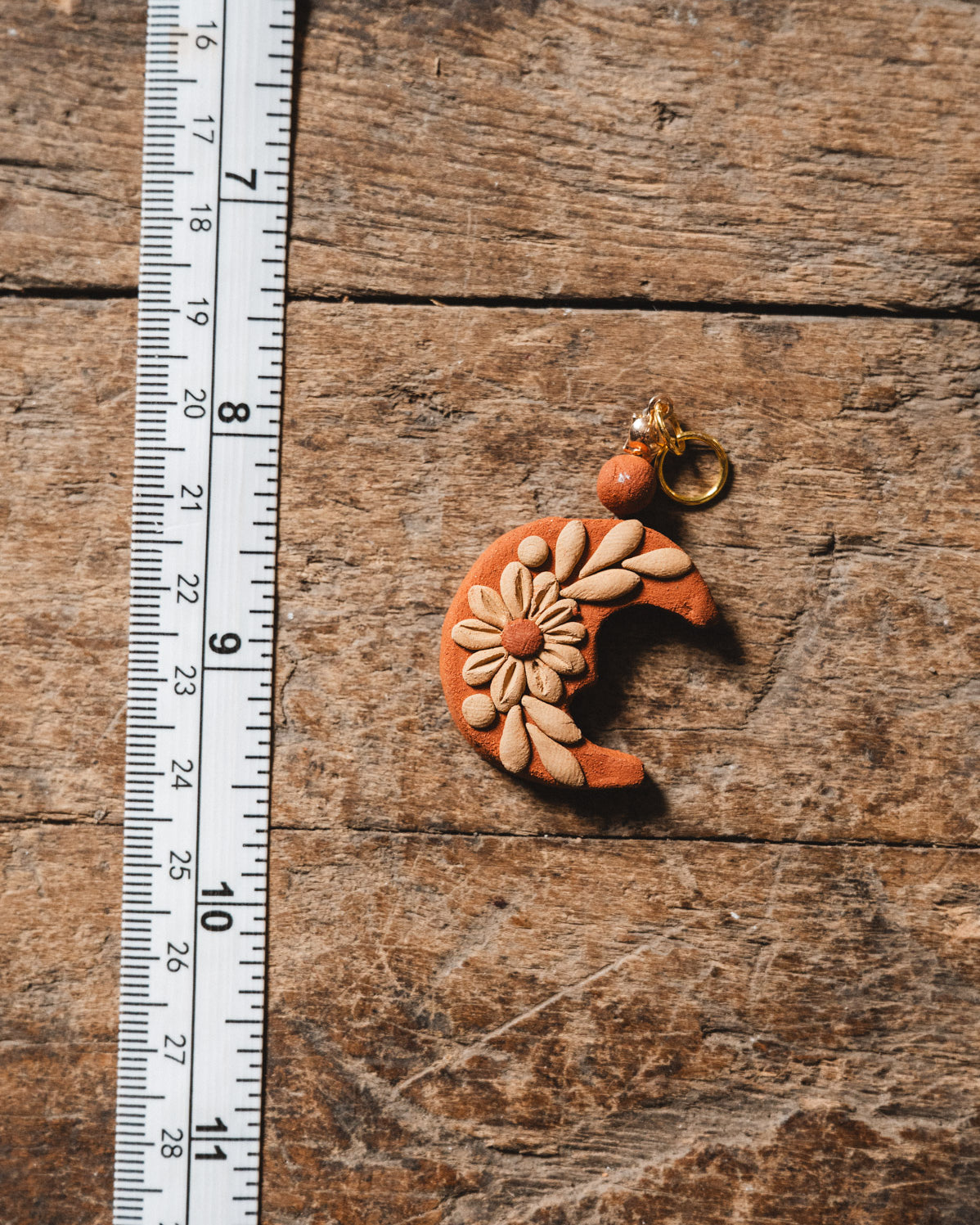 Handmade Filigrana Oaxacan Moon Pendant on wood background with measuring tape