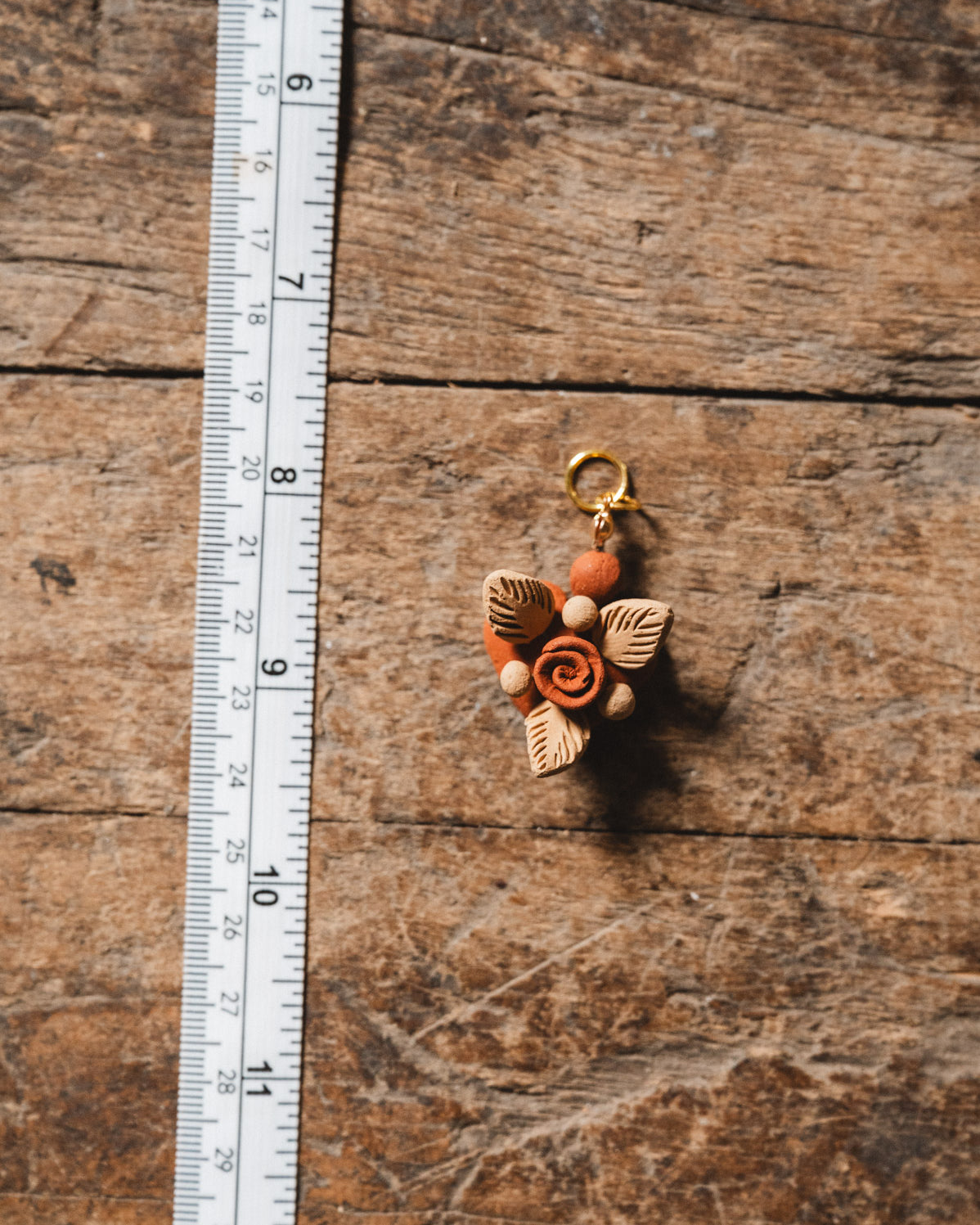 Filigrana heart pendant on wooden floor with ruler