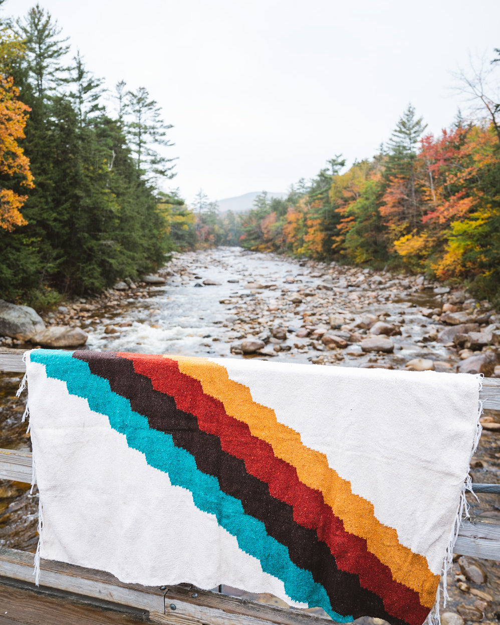 Colorful blanket hanging on side of bridge during autumn