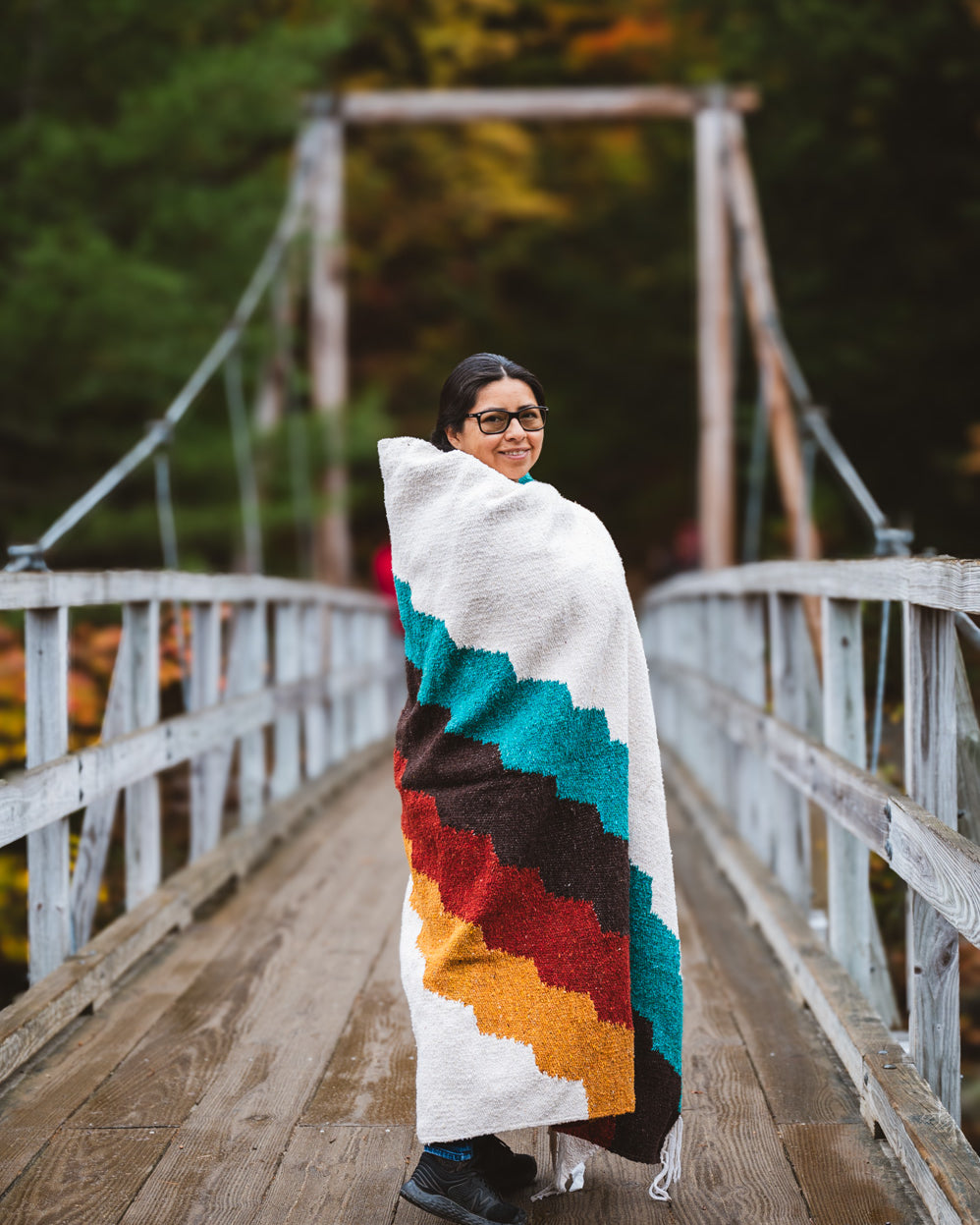 Girl standing on bridge wrapped in colorful blanket