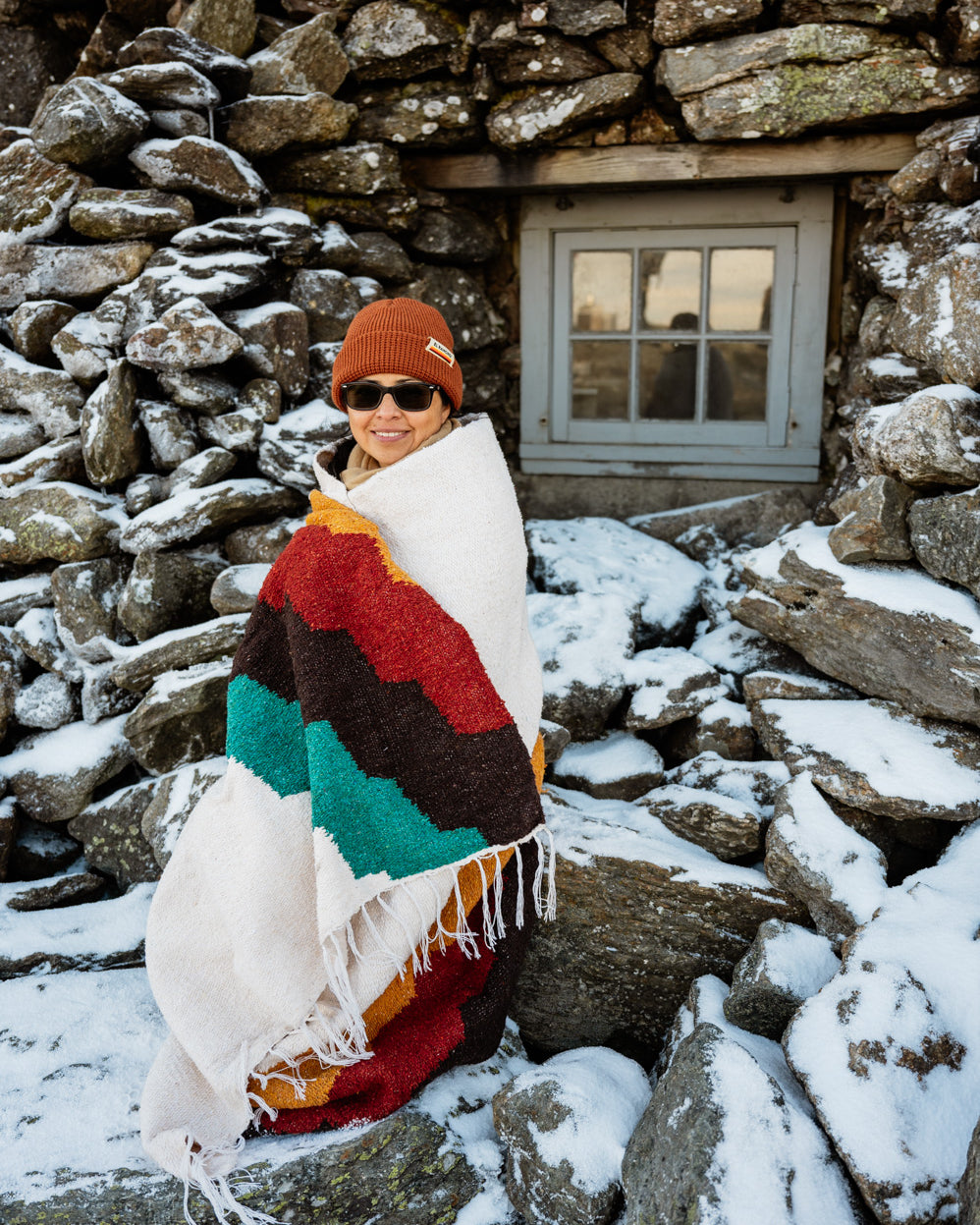 Girl wrapped in blanket in front of stone building during winter