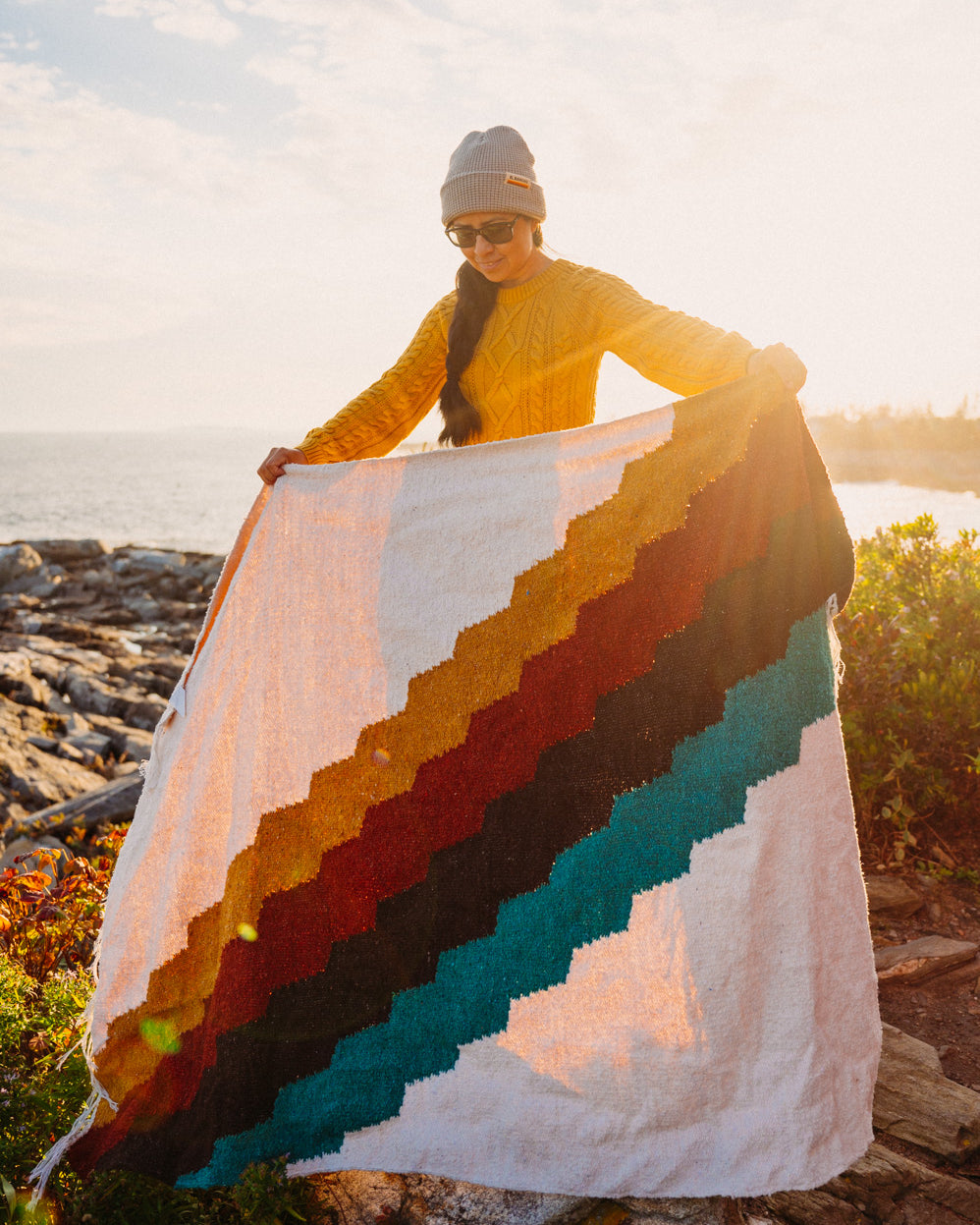 Girl holding colorful blanket at sunset