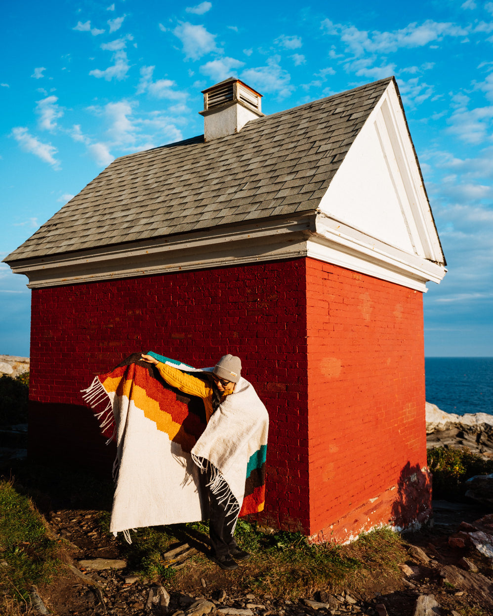 Girl wrapped in colorful blanket in front of red building