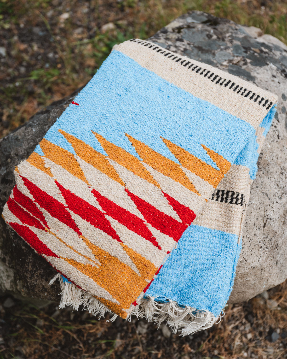 Folded blue and gold mexican blanket sitting on a rock