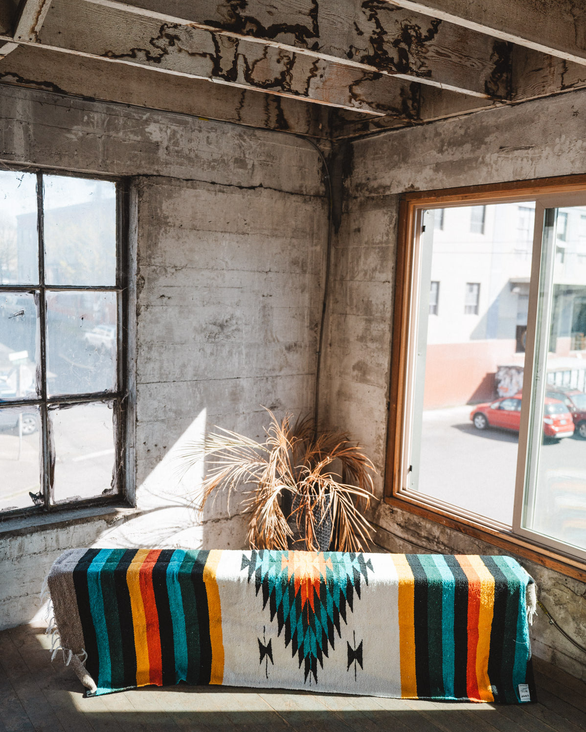 Green white and orange handwoven mexican blanket hanging in urban loft