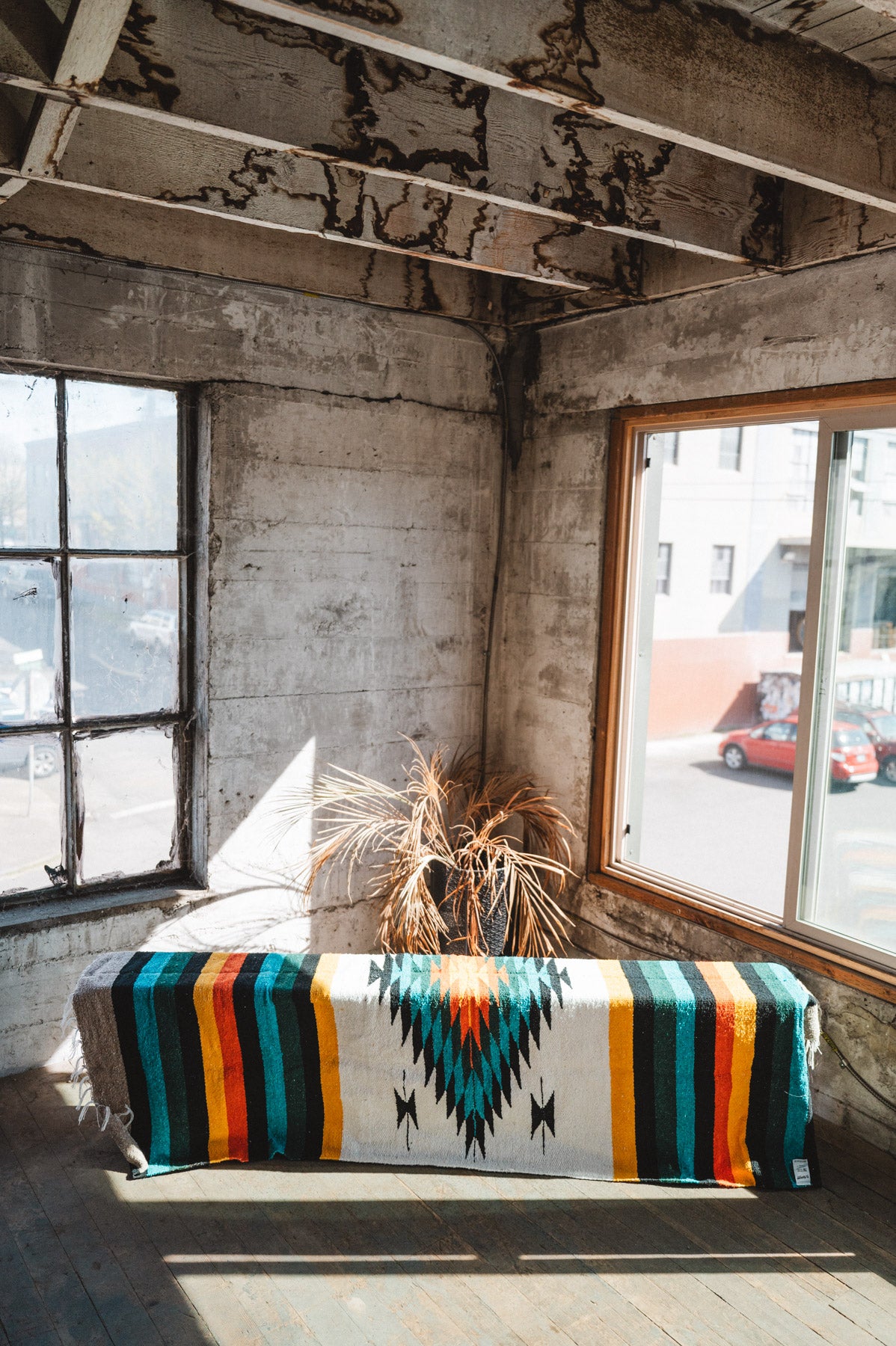 Green white and orange handwoven mexican blanket hanging in urban loft