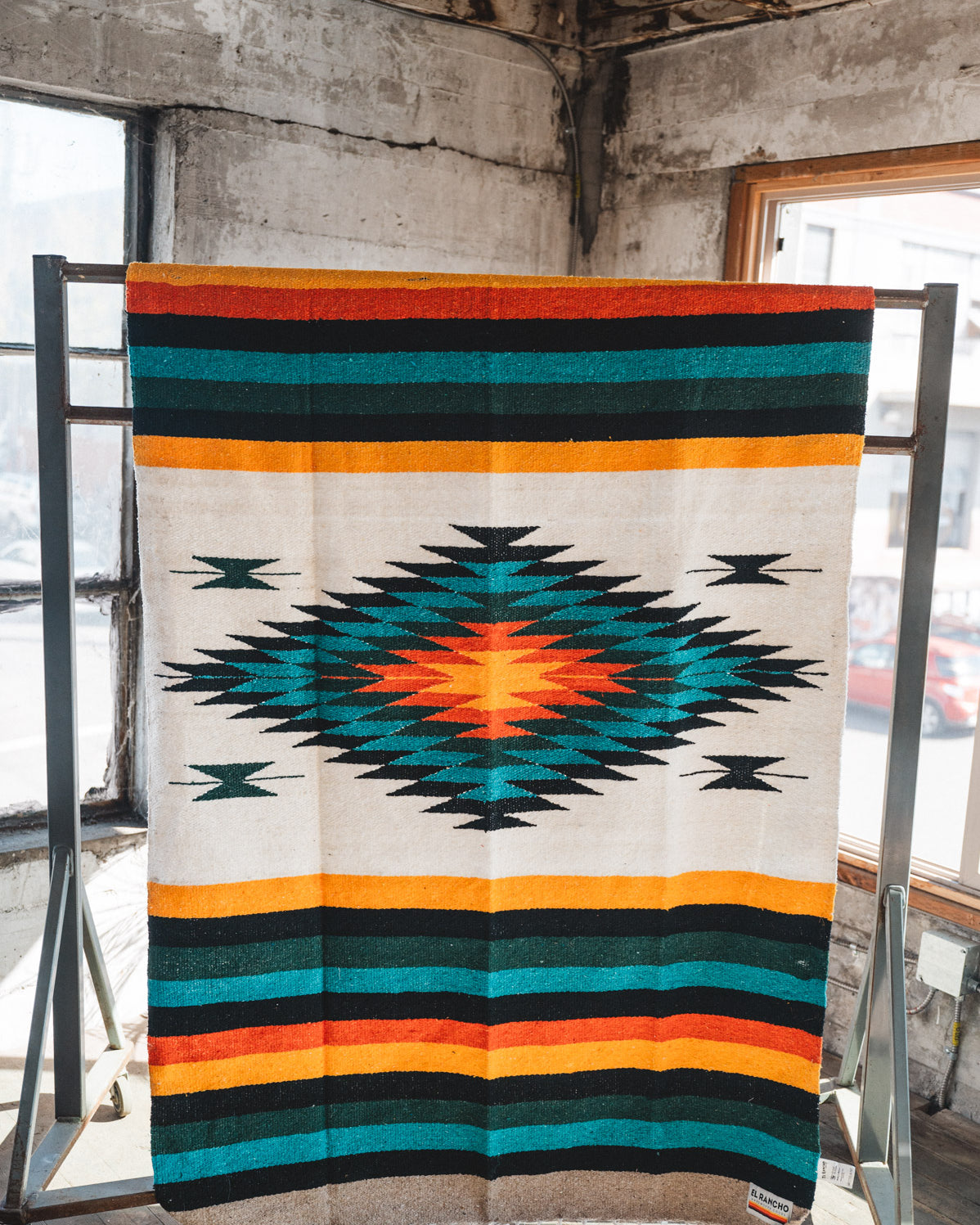 Green white and orange handwoven mexican blanket hanging in urban loft