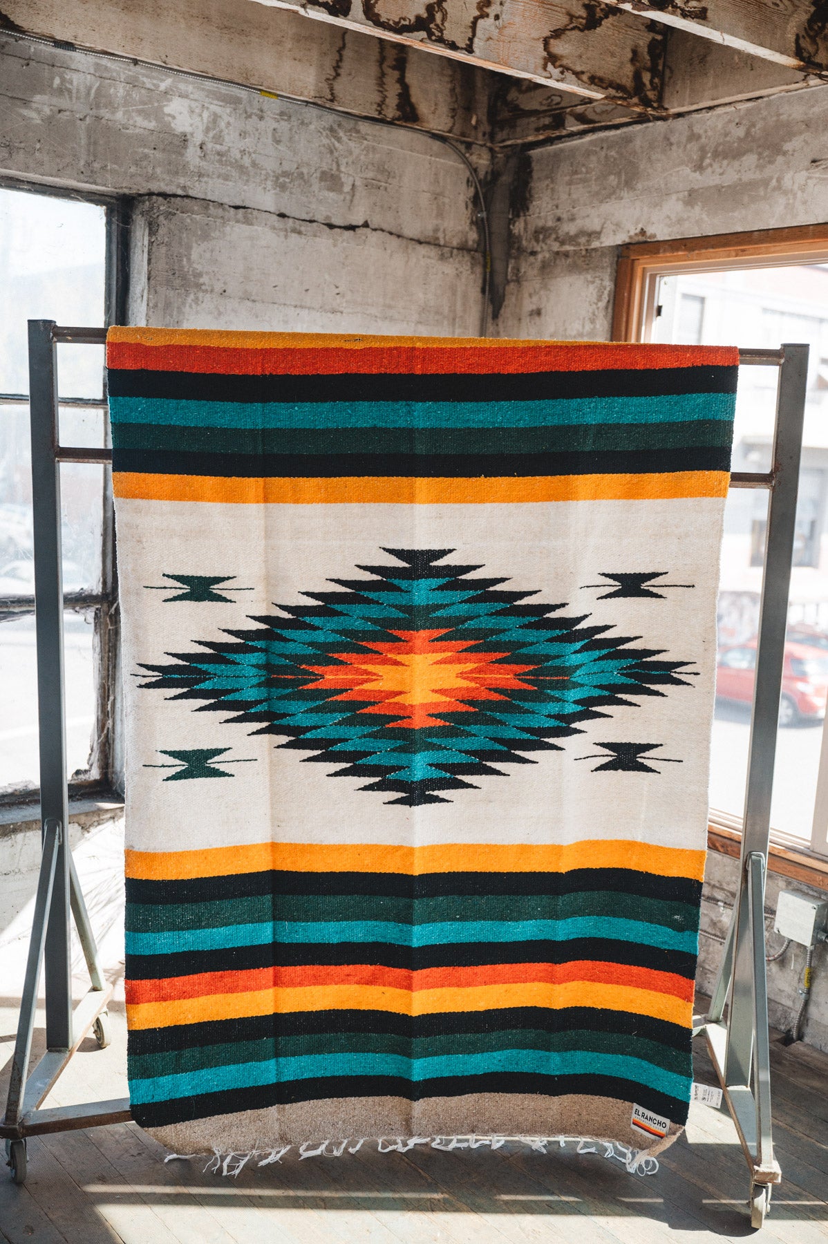 Green white and orange handwoven mexican blanket hanging in urban loft